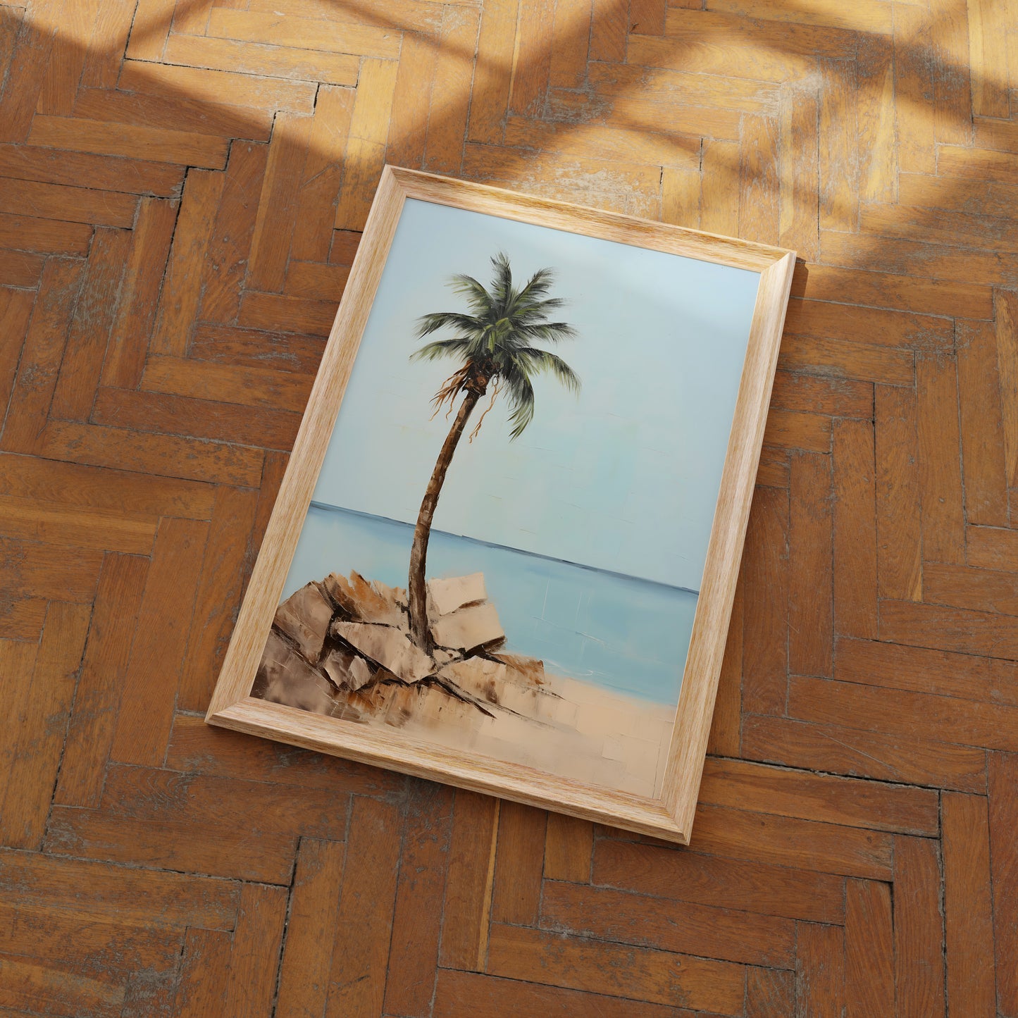 A framed picture of a palm tree on a wooden parquet floor.