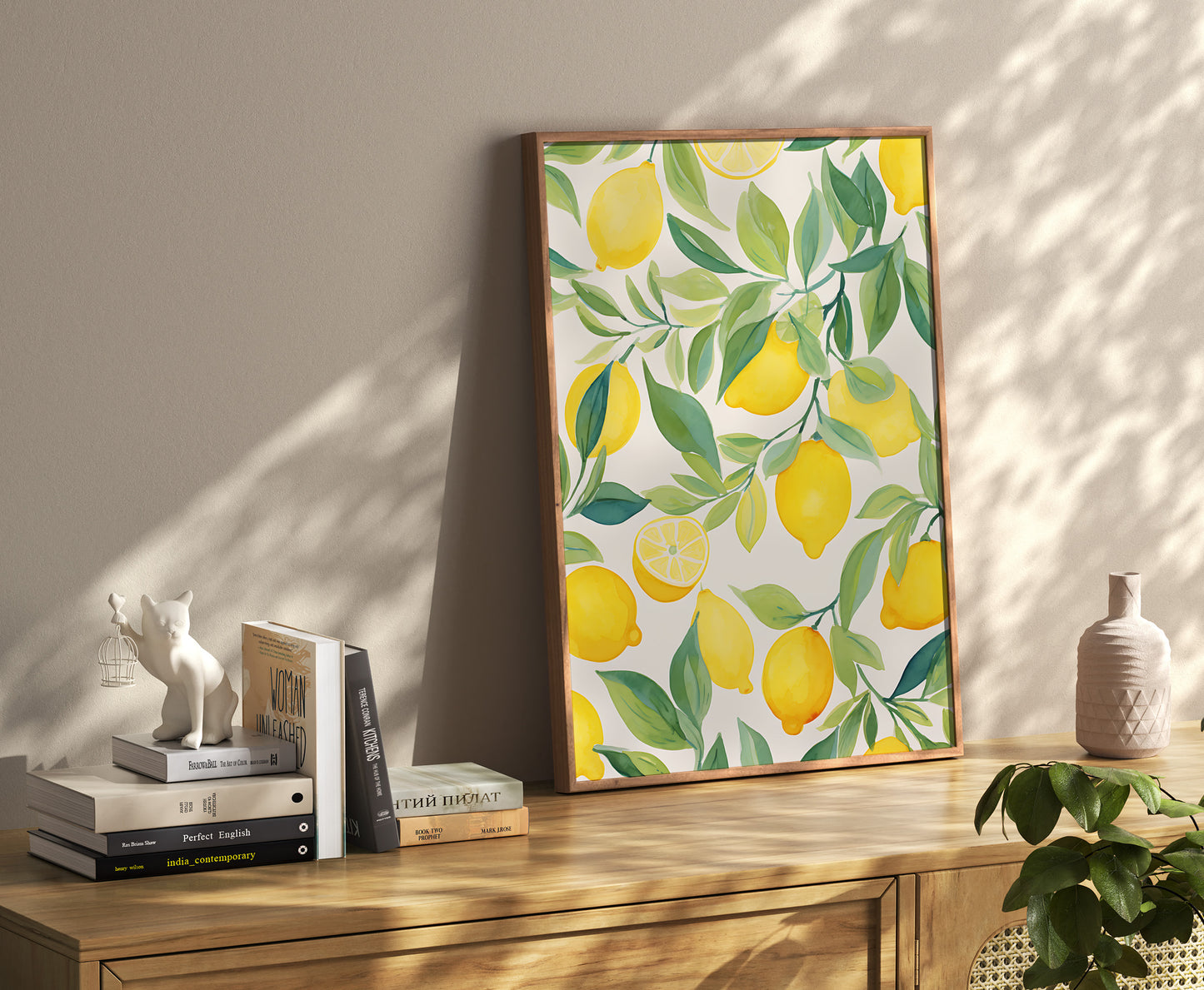 A framed painting with a lemon pattern leaning against a wall on a wooden sideboard.