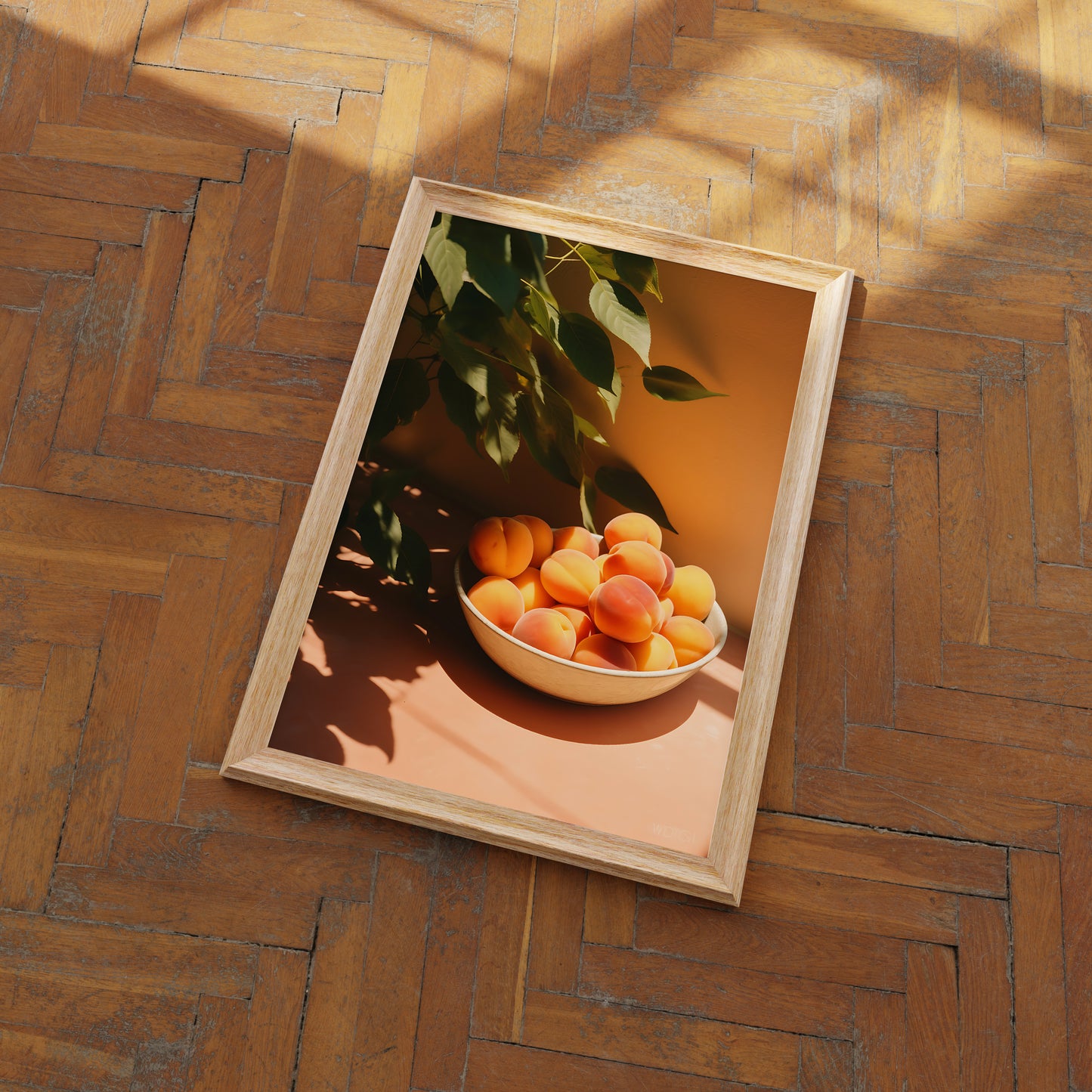 A framed picture of a bowl of apricots on a floor with herringbone pattern wood.