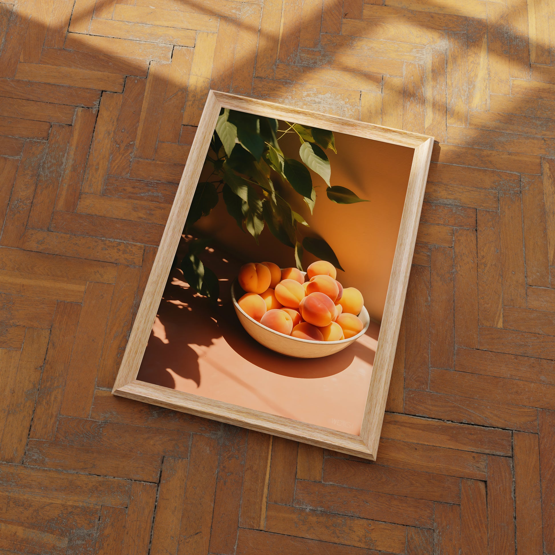 A framed picture of a bowl of apricots on a floor with herringbone pattern wood.