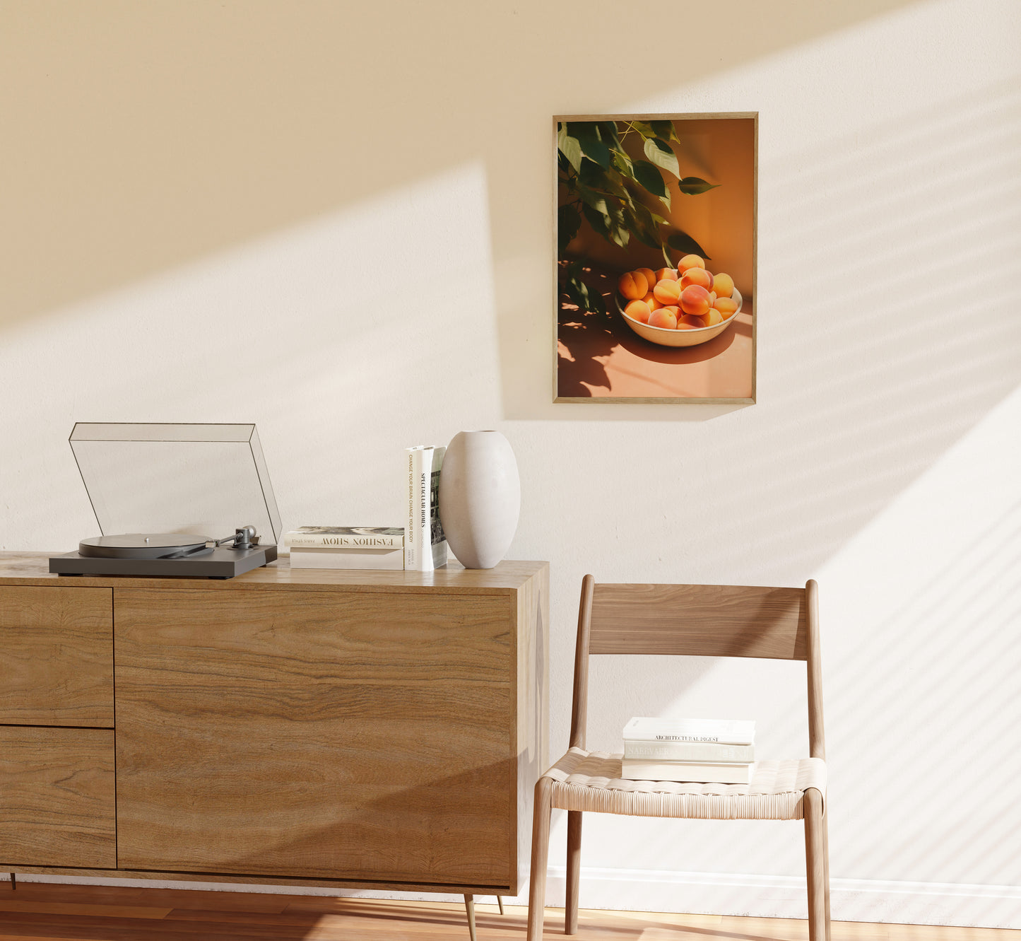 A cozy room corner with a wooden cabinet, record player, chair, and framed art of fruit on the wall.