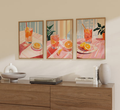 Three framed illustrations of a refreshing orange drink on a table, displayed on a wall above a sideboard.