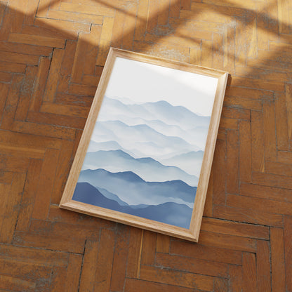 A framed picture of blue mountain ranges on a herringbone wood floor.