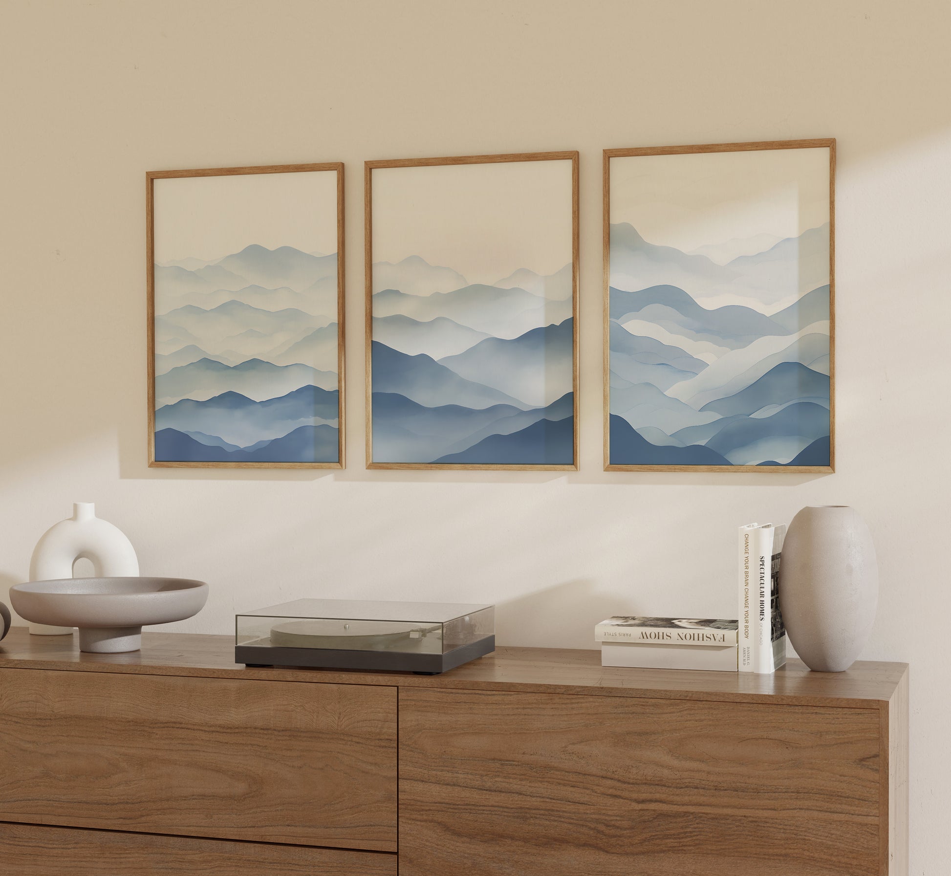 Three framed mountain landscape art pieces hanging above a wooden sideboard.