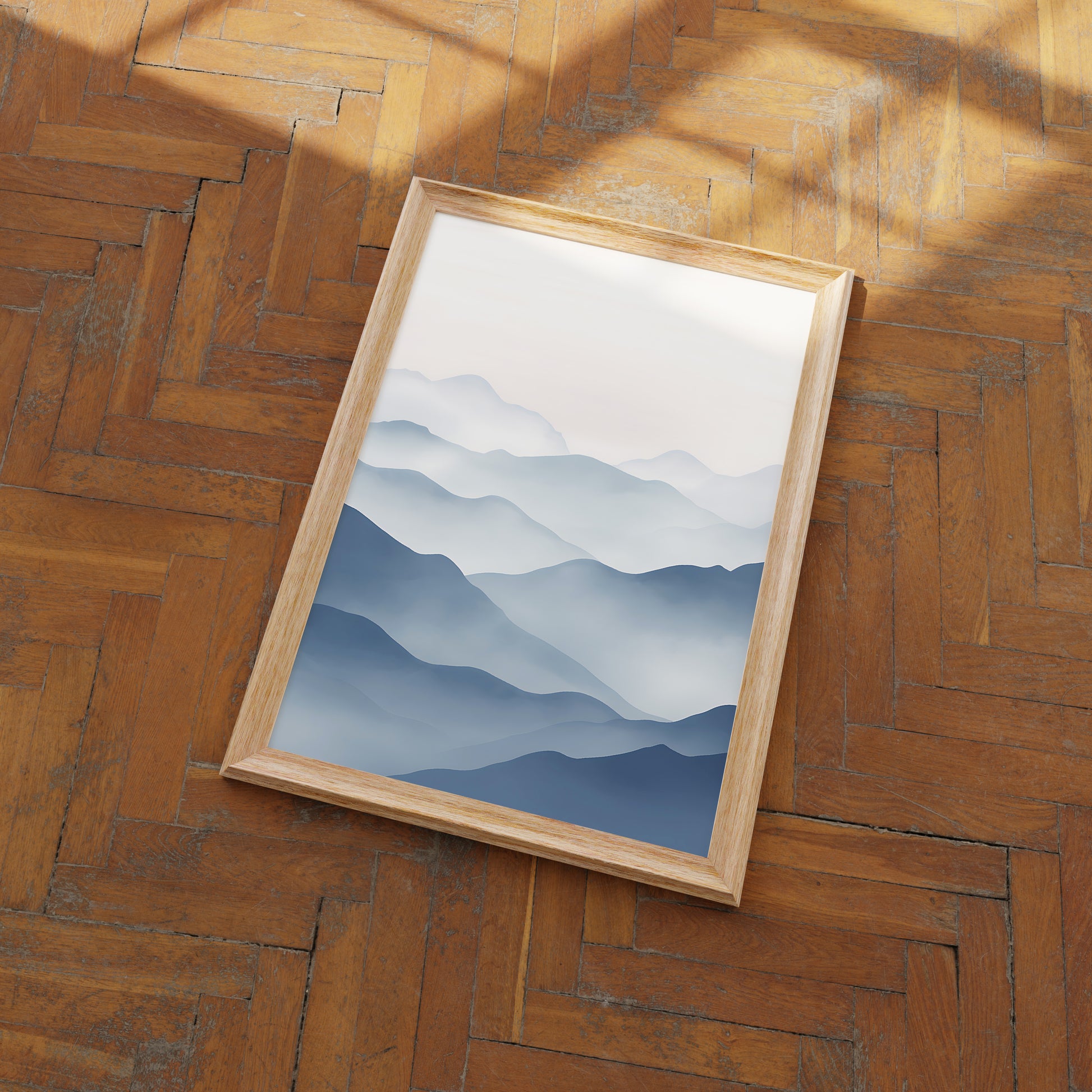 A framed picture of blue mountains on a wooden floor.