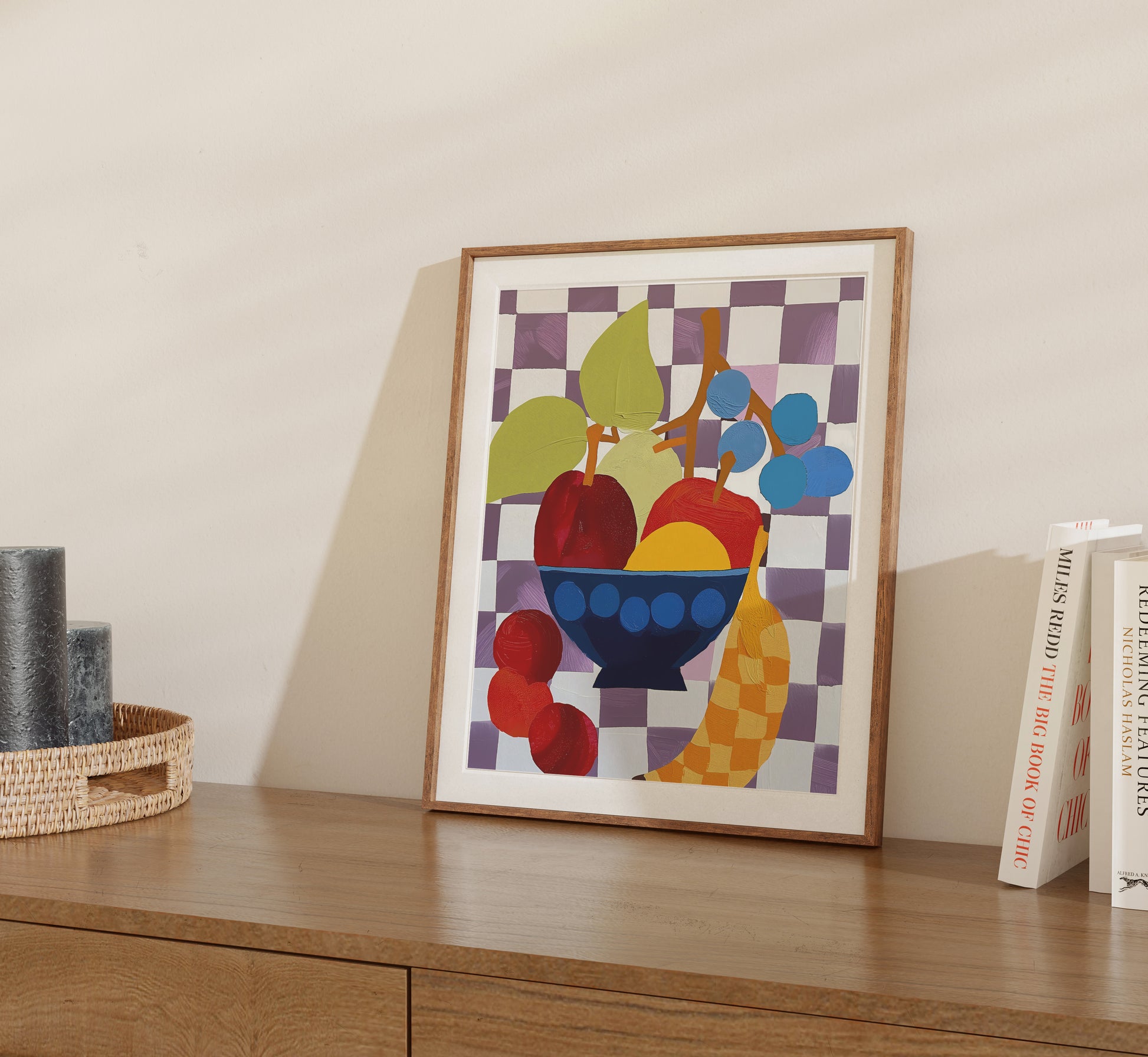A framed abstract painting of fruit on a checkered background displayed on a wooden shelf.