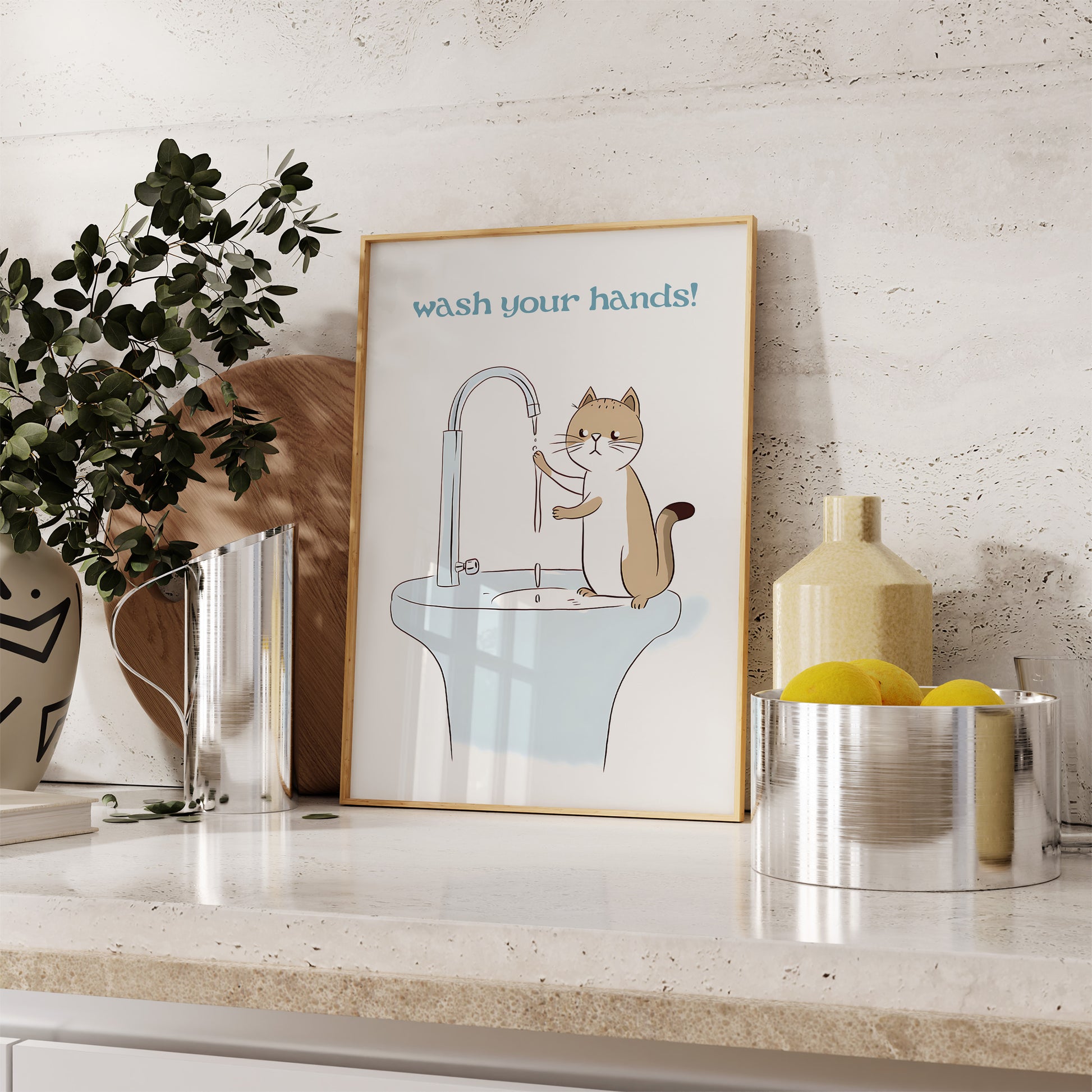 A framed poster with a cartoon cat at a sink and "wash your hands!" text, placed on a kitchen counter.