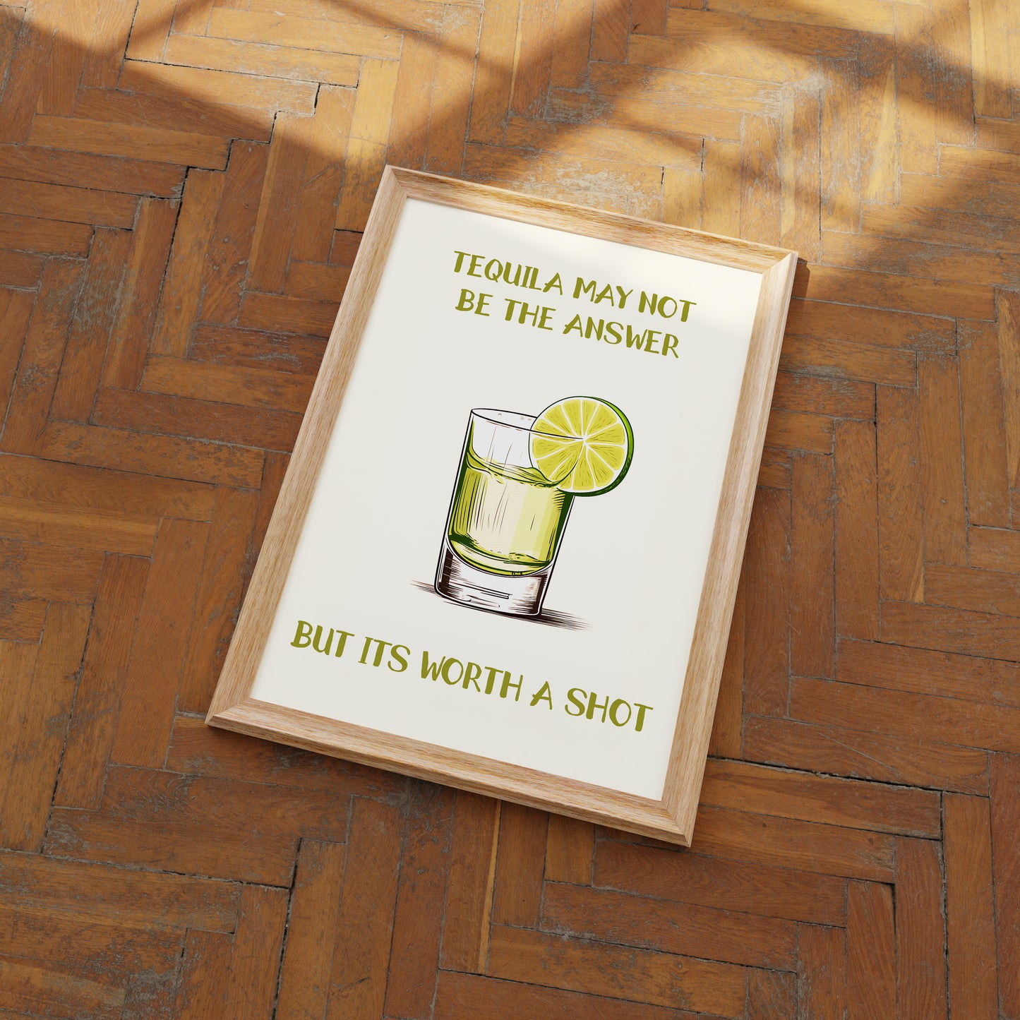 A framed poster on a wooden floor with a humorous quote about tequila and an illustration of a drink.