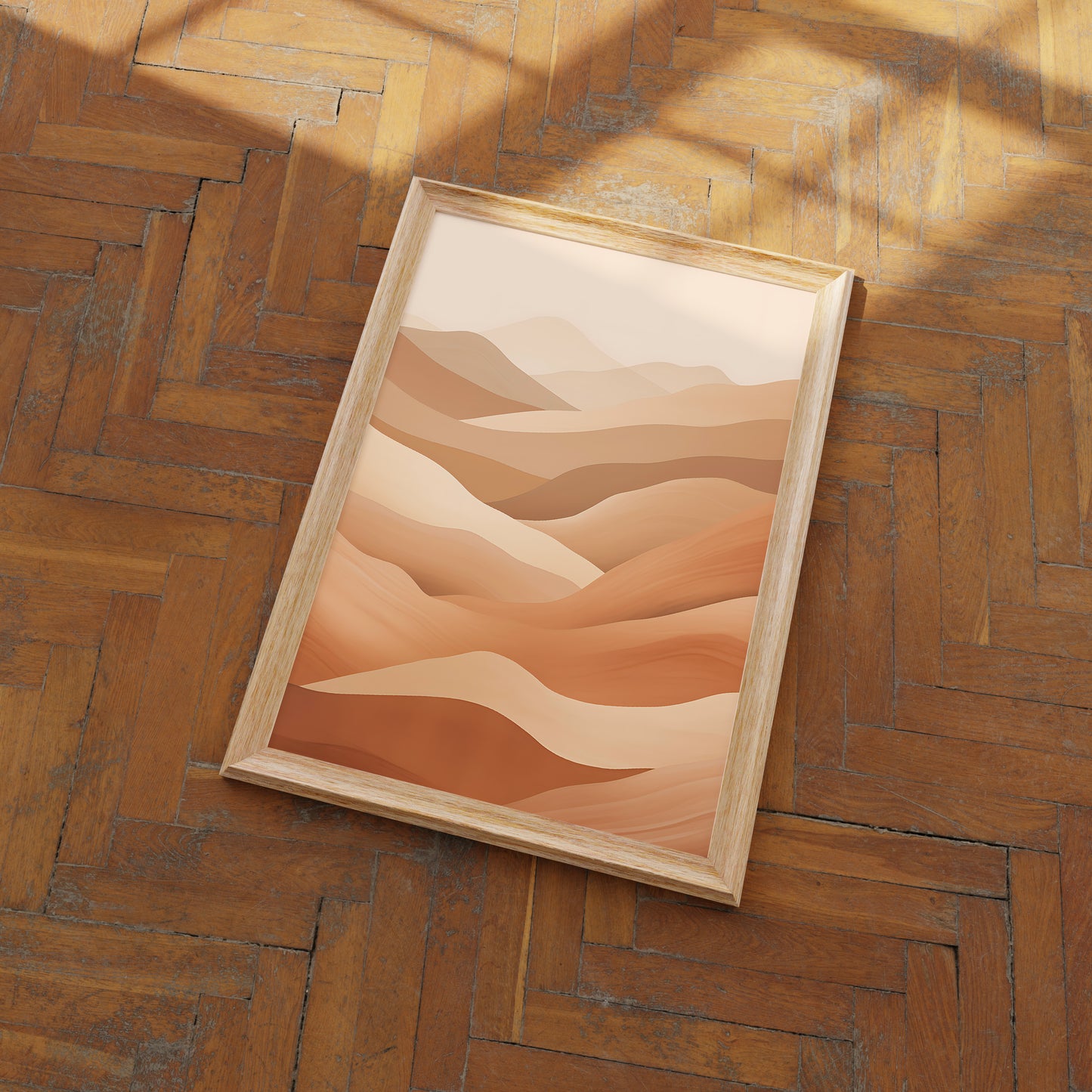 A framed abstract desert landscape painting leaning on a herringbone wood floor.