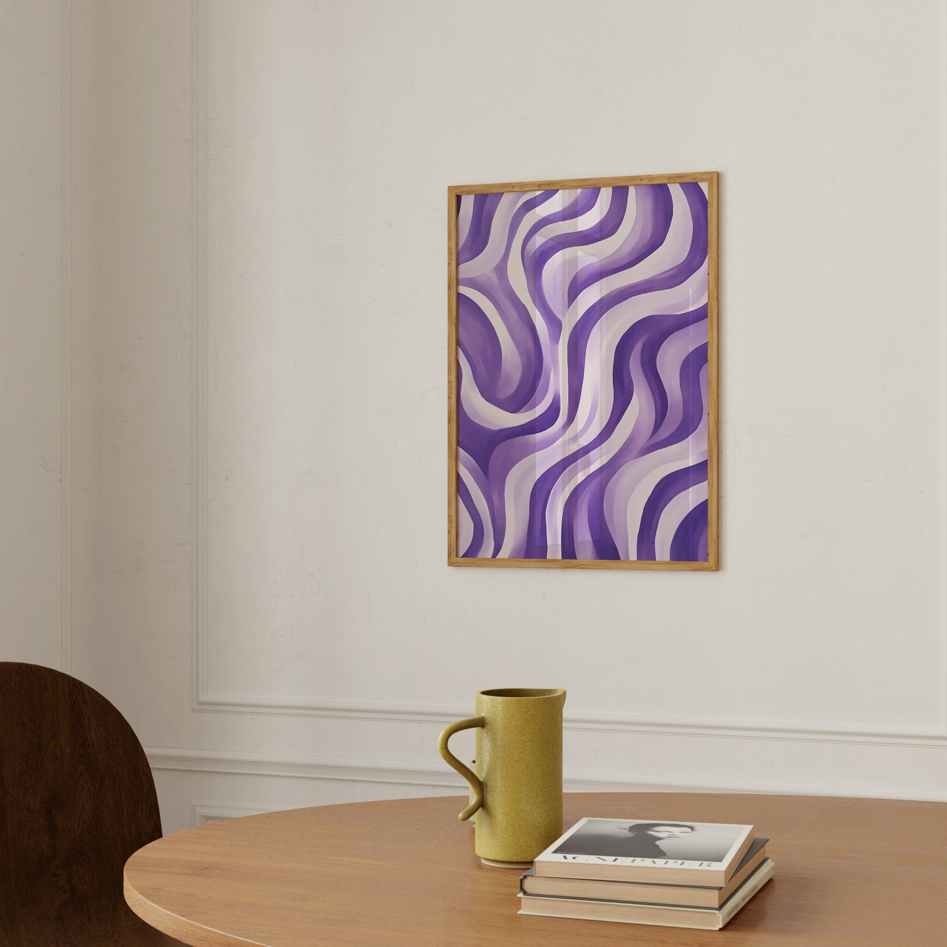 Abstract purple artwork on a wall above a table with a yellow mug and books.