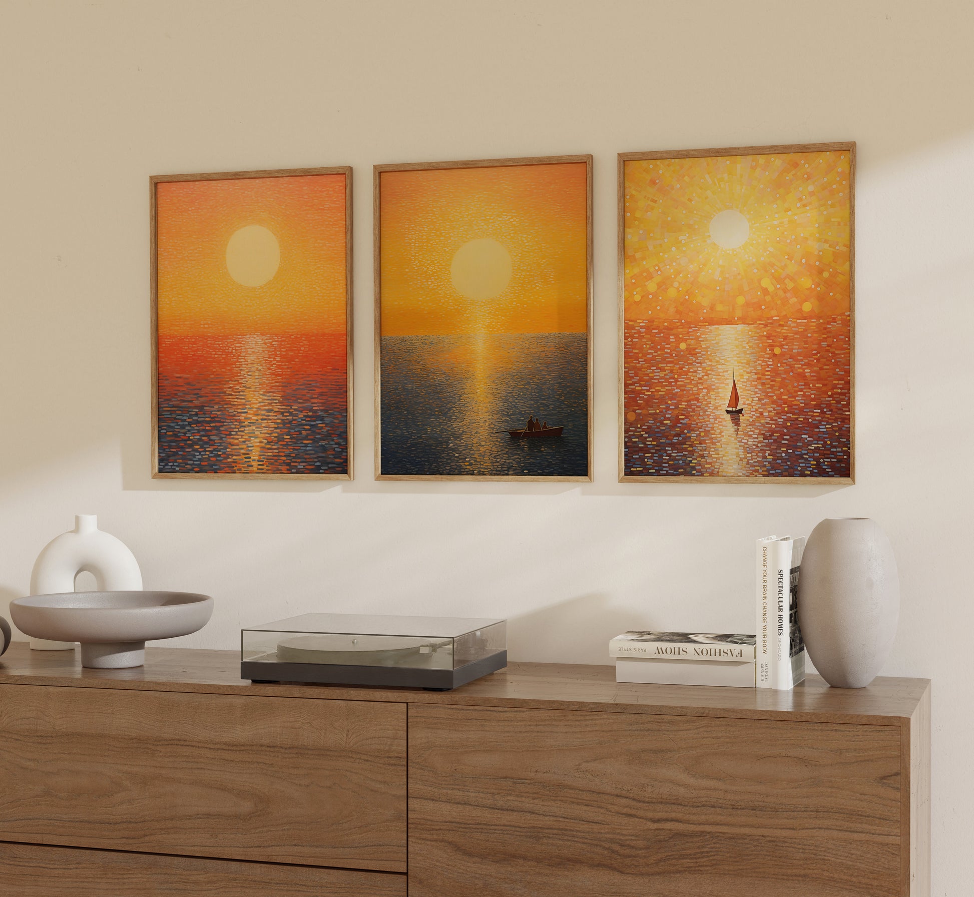 Three framed paintings of sunsets over water, displayed above a wooden sideboard.