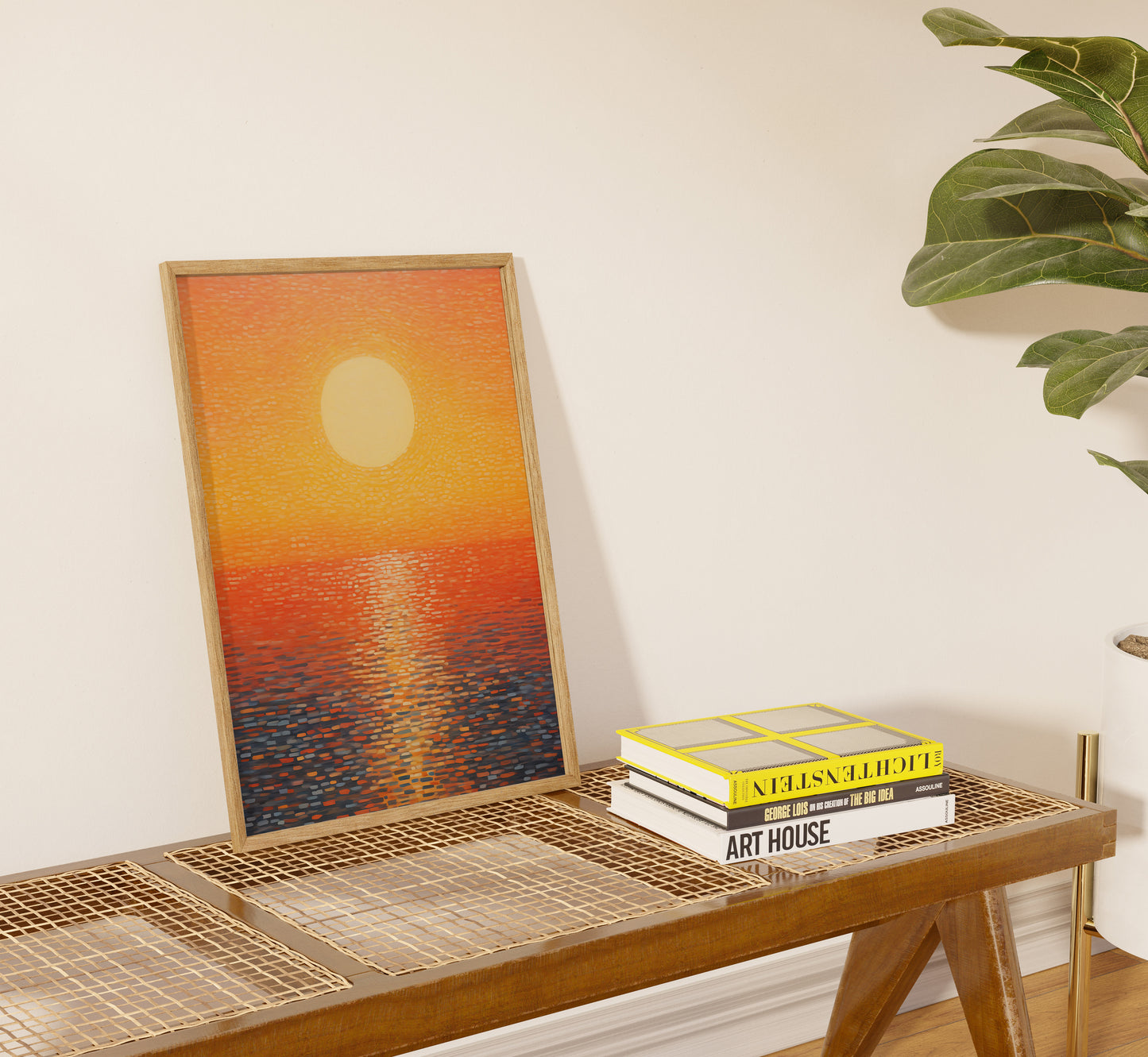 Framed sunset painting on a wall above a console with books and a plant.