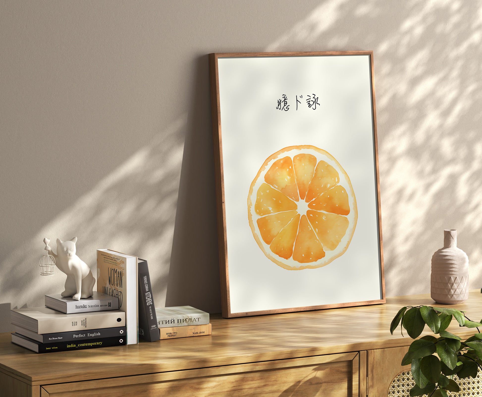 A framed poster of an orange slice on the floor leaning against a wall, beside a shelf with books and decor.