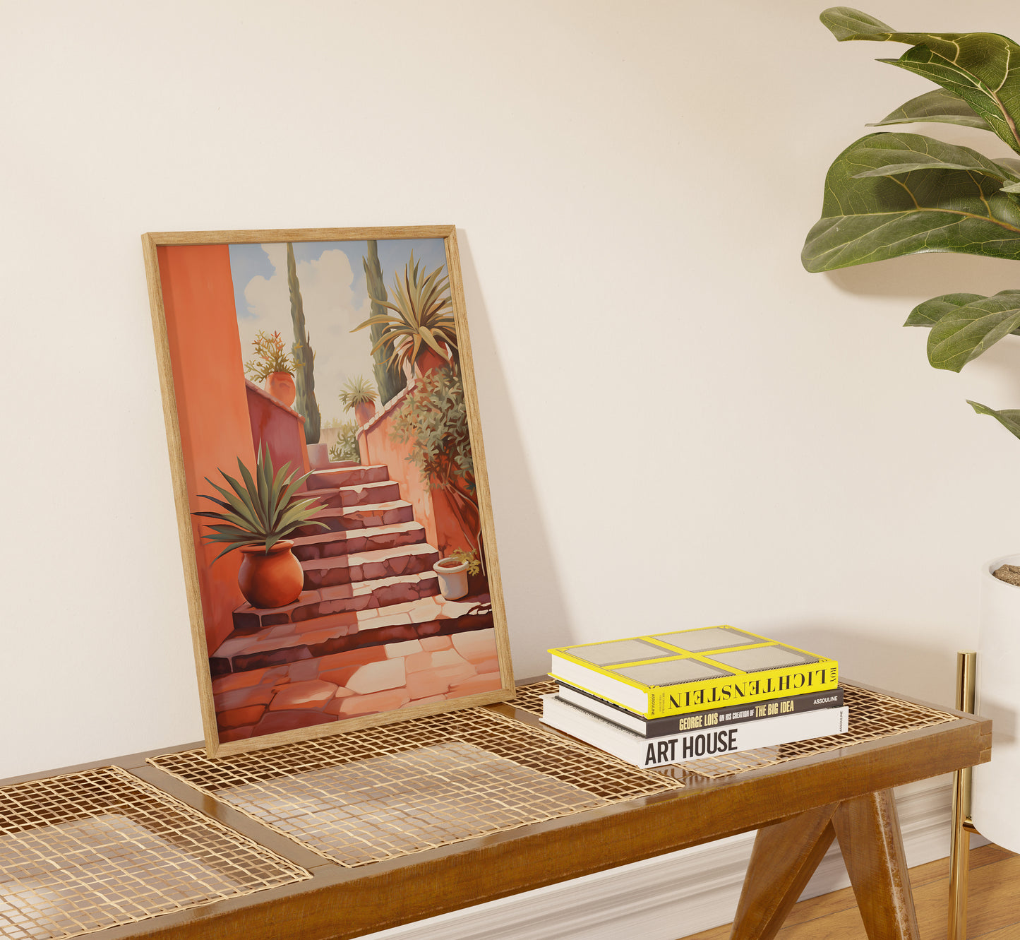 A framed painting of stairs and plants on a console table with books next to it.