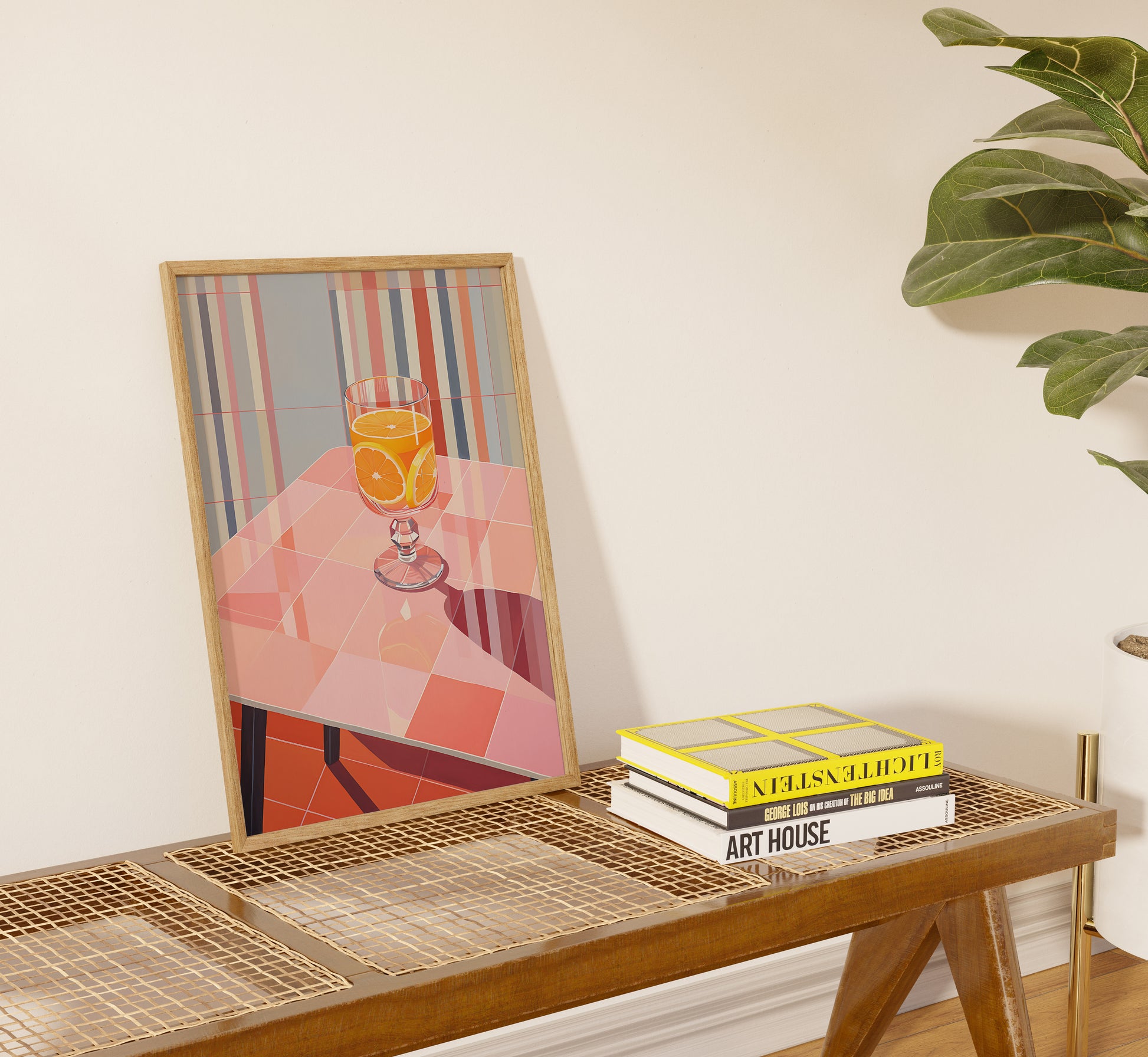 A framed geometric art piece on a console table with books and a leafy plant beside it.