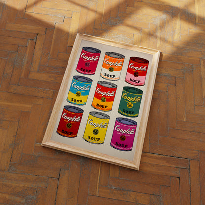 A framed pop art piece featuring colorful Campbell's soup cans on a wooden floor.