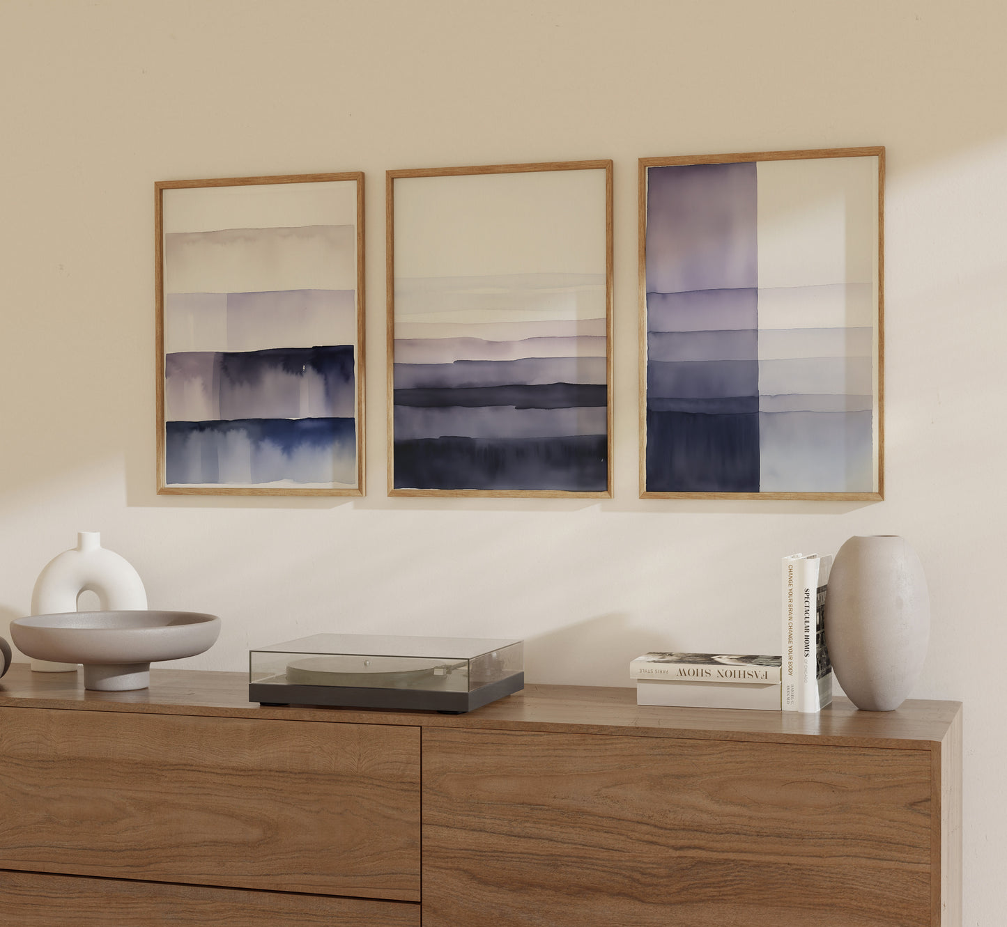 Three framed abstract paintings above a wooden sideboard with decorative items.