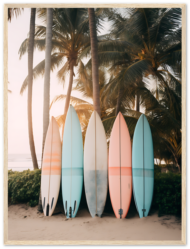 Five colorful surfboards standing upright on a sandy beach with palm trees in the background at sunset.