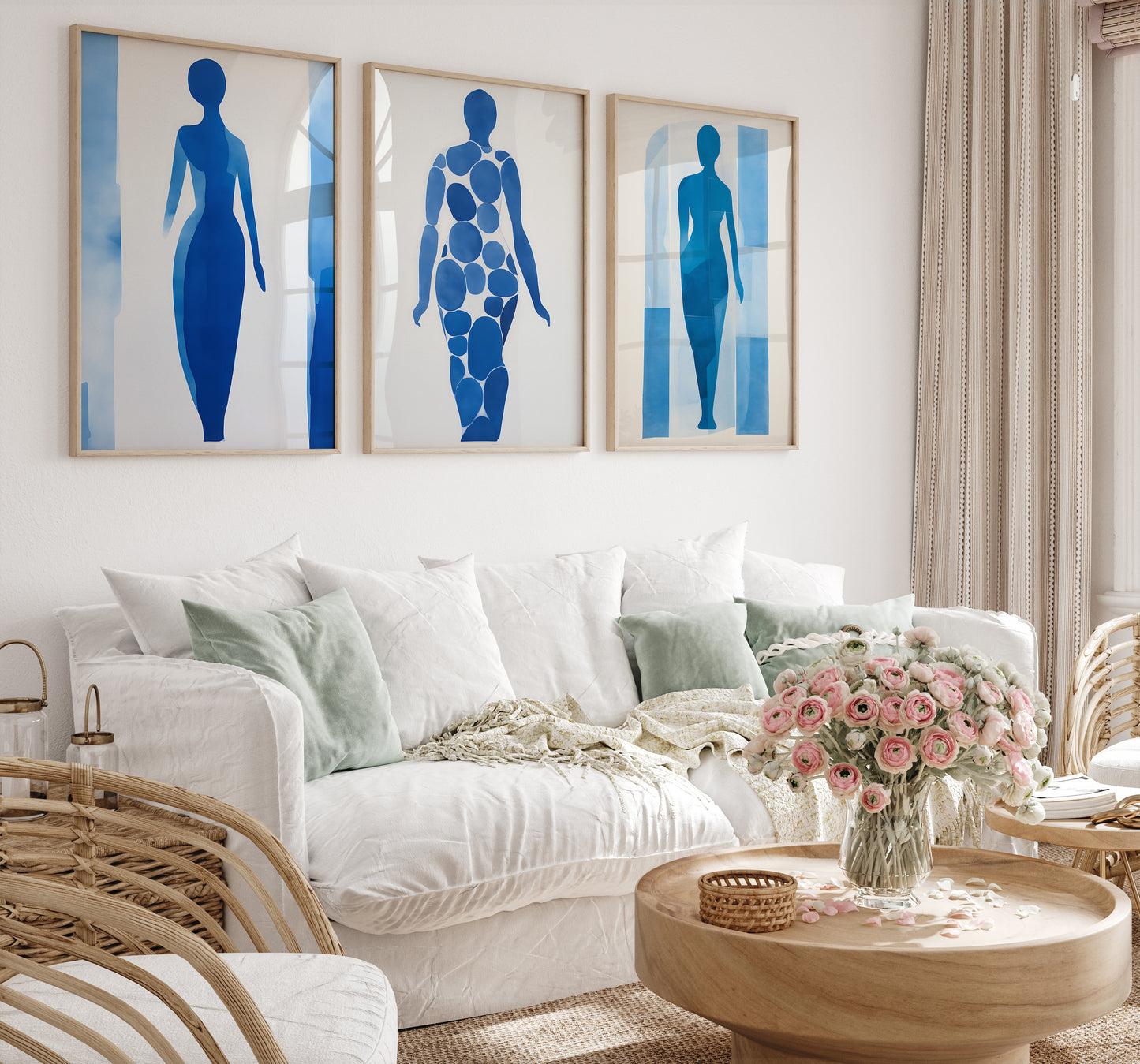 Three abstract blue human silhouette artworks on a white living room wall above a sofa.