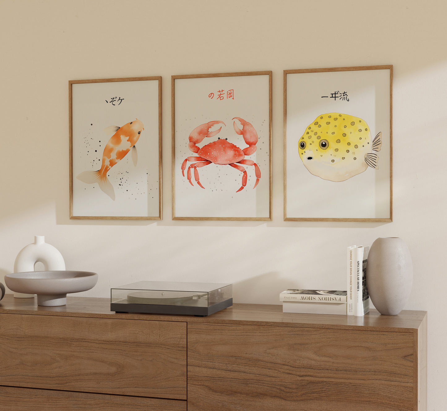 Three framed illustrations of sea creatures—a koi fish, a crab, and a pufferfish—on a wall above a wooden sideboard.