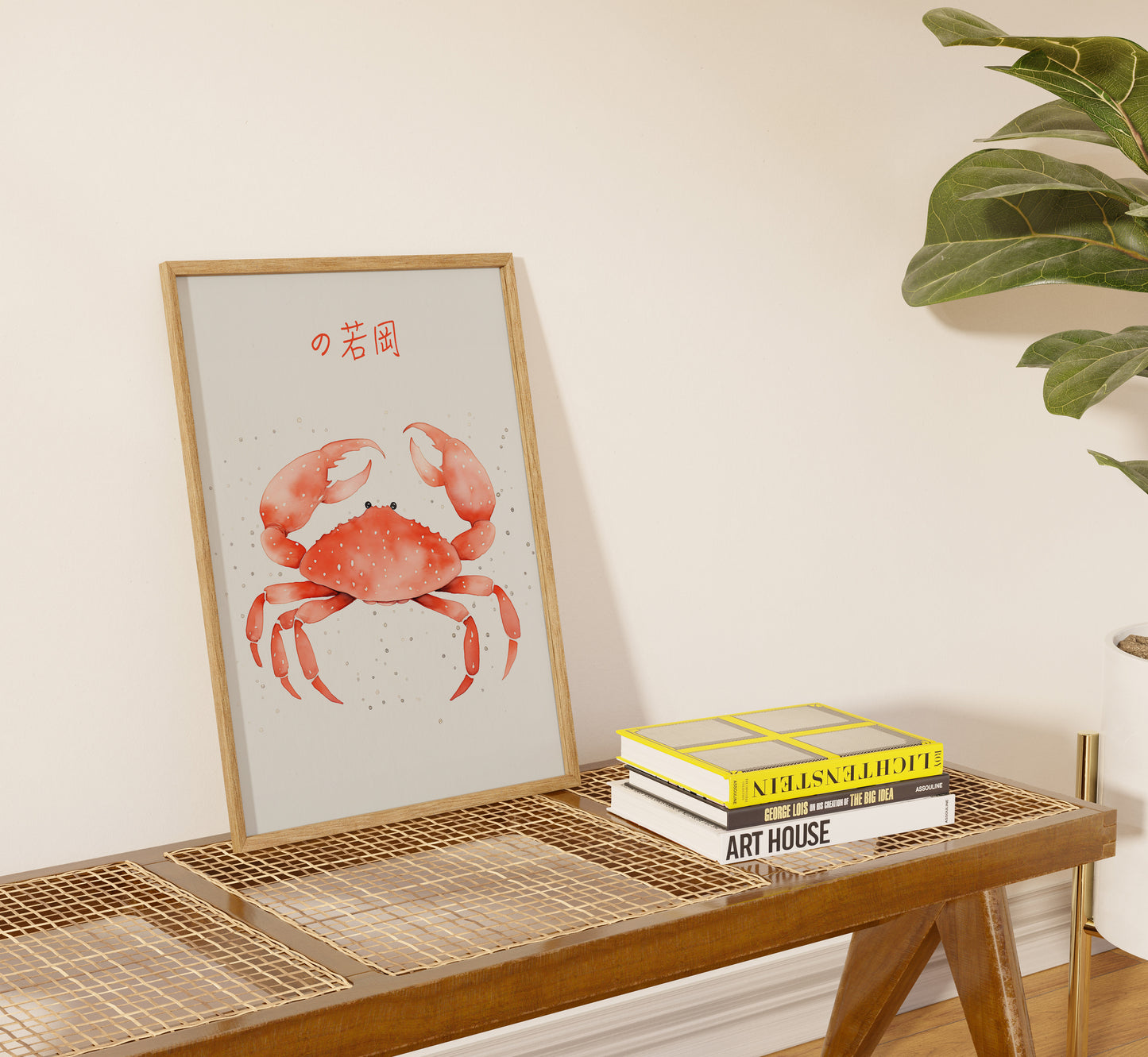 Framed crab illustration on a shelf with books and a plant.