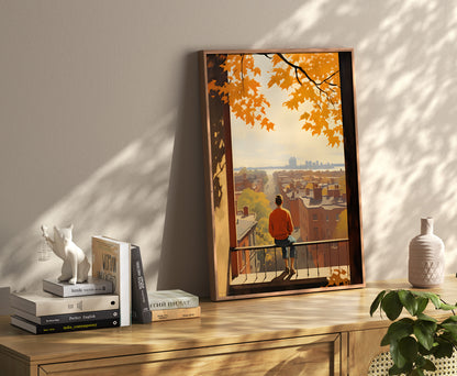 A framed artwork of a person on a balcony overlooking an autumnal cityscape, displayed in a cozy room.