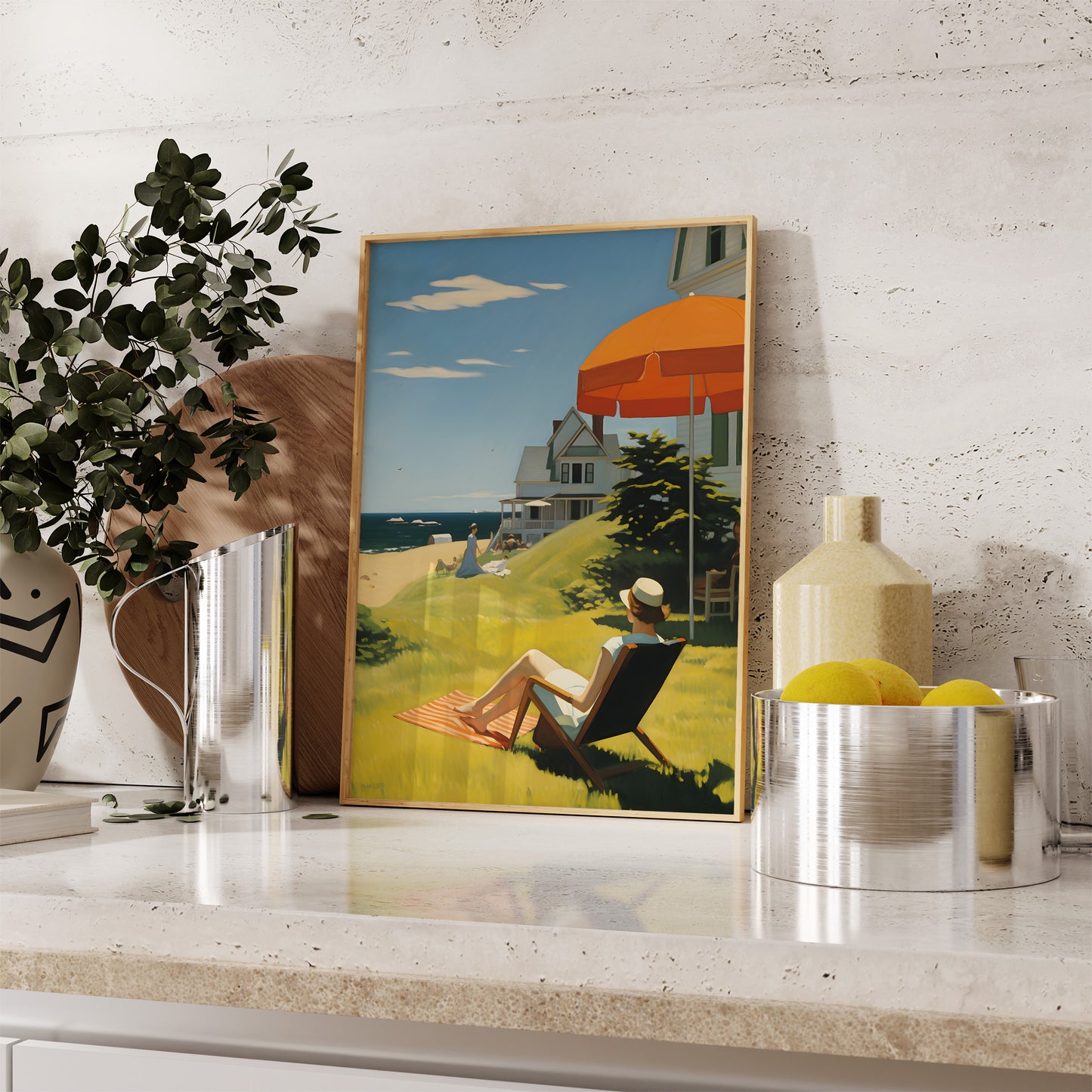 A framed beach painting displayed on a mantle with decorative items.