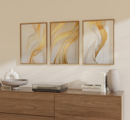 Three abstract art frames above a wooden sideboard with decorative items.