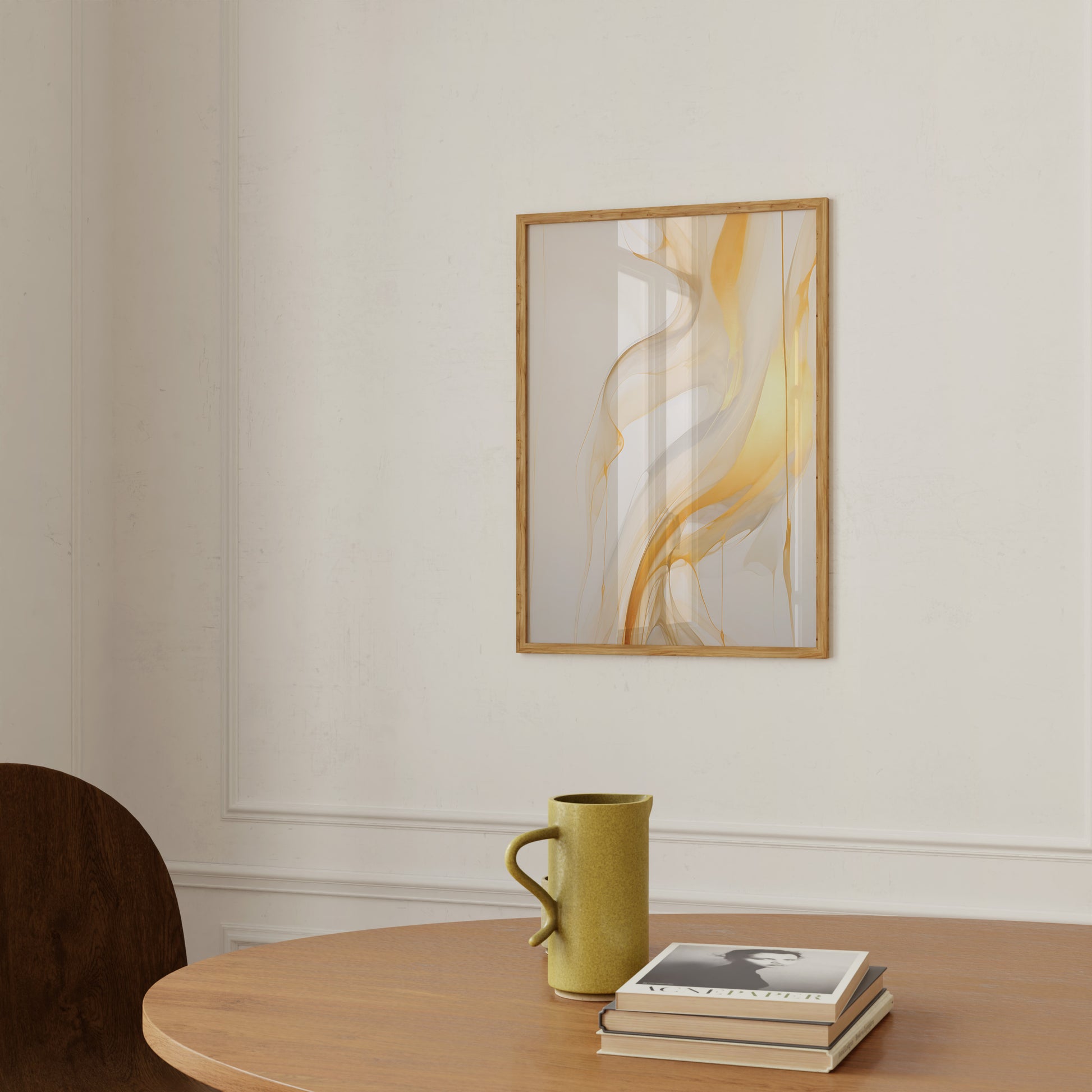 Abstract art in frame on a wall above a table with a mug and books.