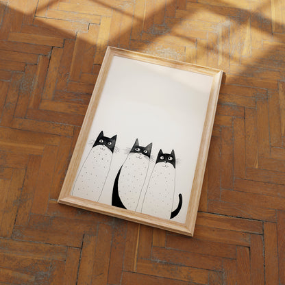 A framed illustration of three cartoon cats on a wooden floor.