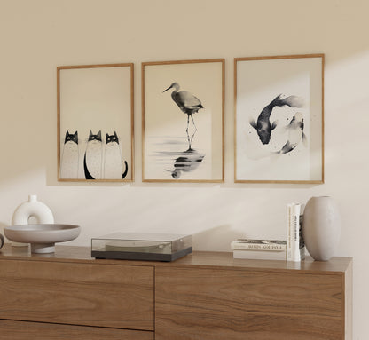 Three framed artworks above a wooden sideboard with decorative items and books.