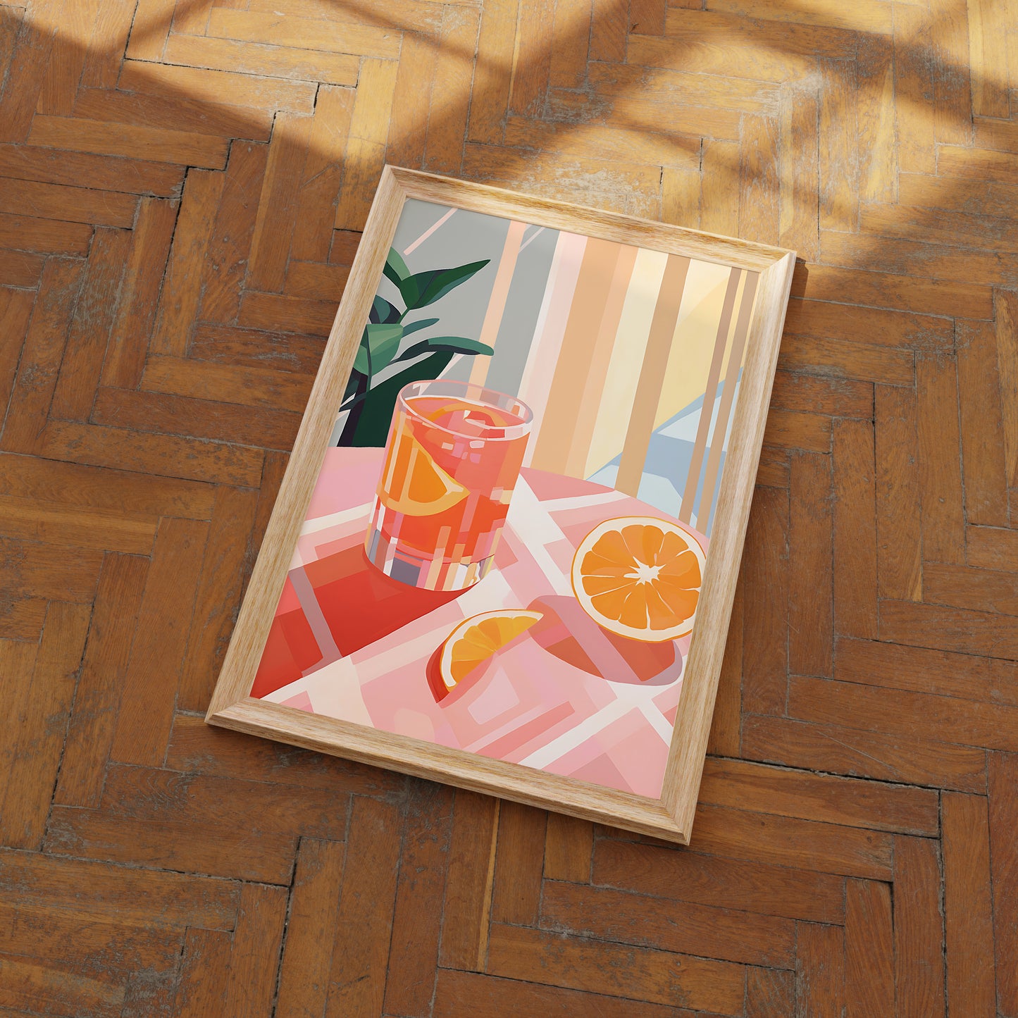 Framed artwork of a sliced orange and a drink on a wooden floor.