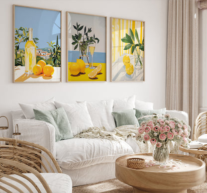 Three framed citrus-themed art pieces above a cozy white sofa with a flower arrangement on the coffee table.