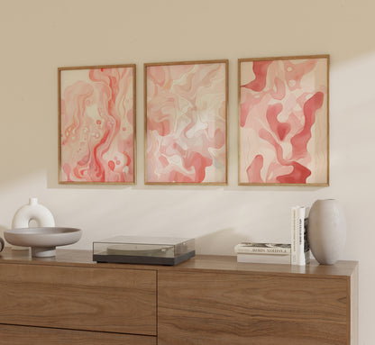Three abstract paintings on a wall above a wooden cabinet with decorative items.