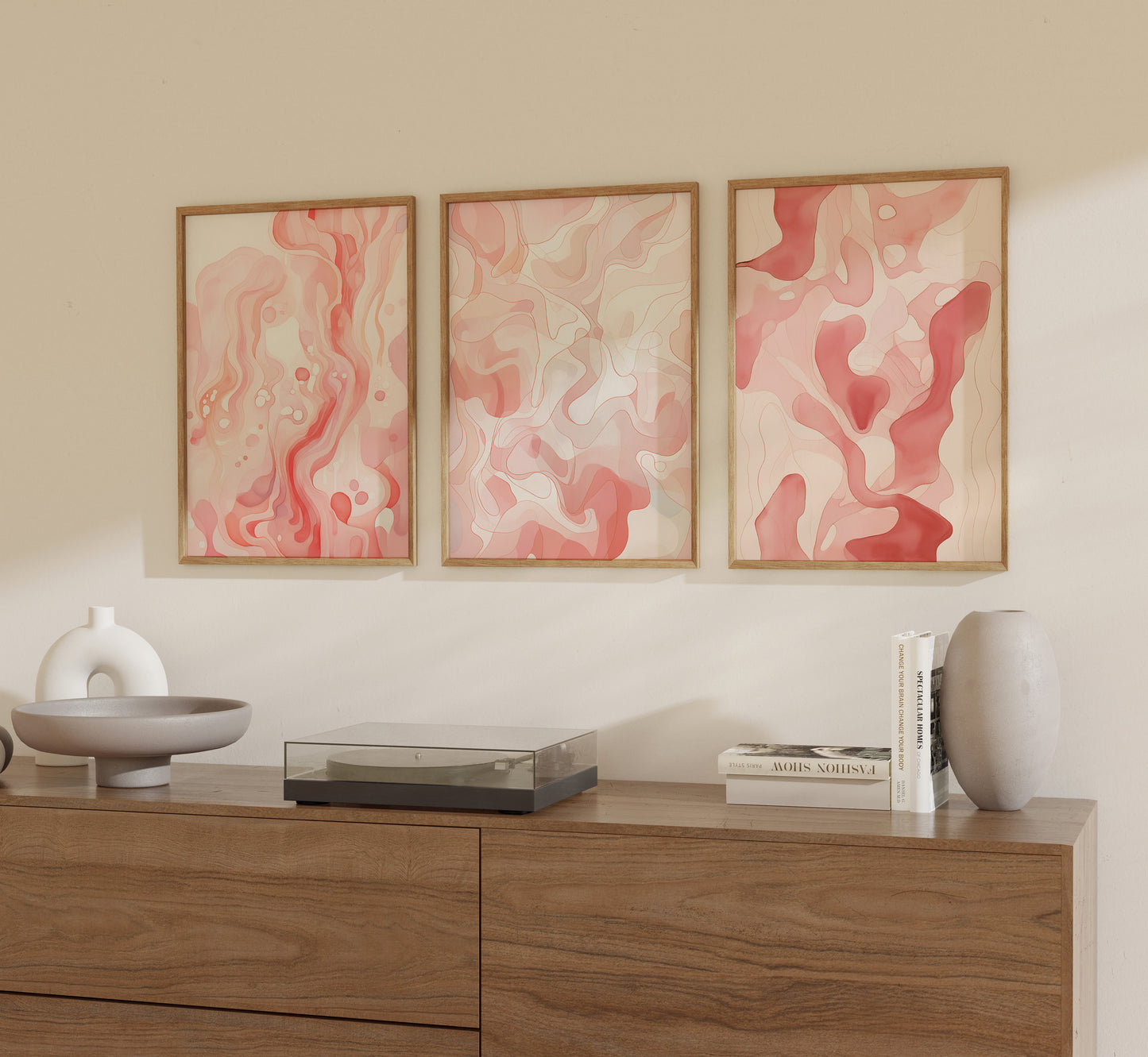 Three abstract paintings on a wall above a wooden sideboard with decorative items.