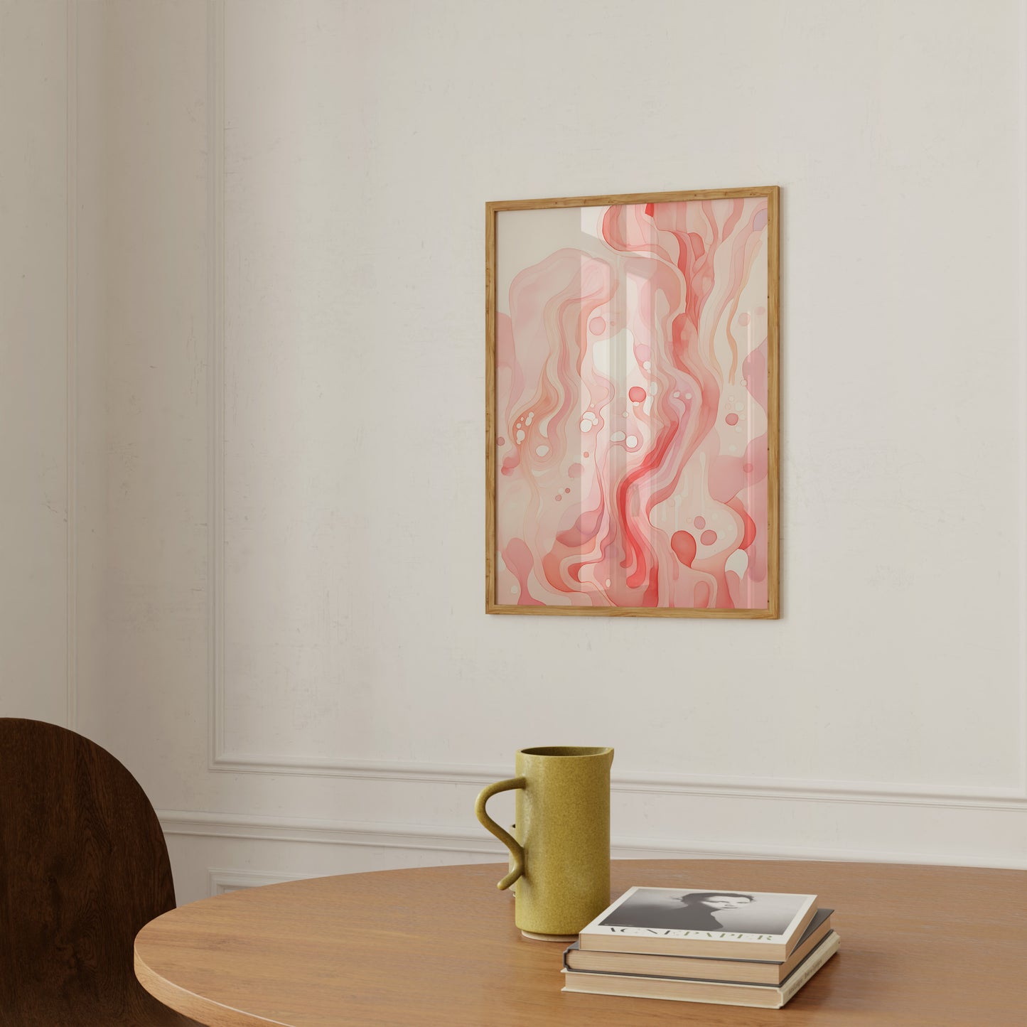 A framed abstract artwork on a wall above a table with a mug and books.