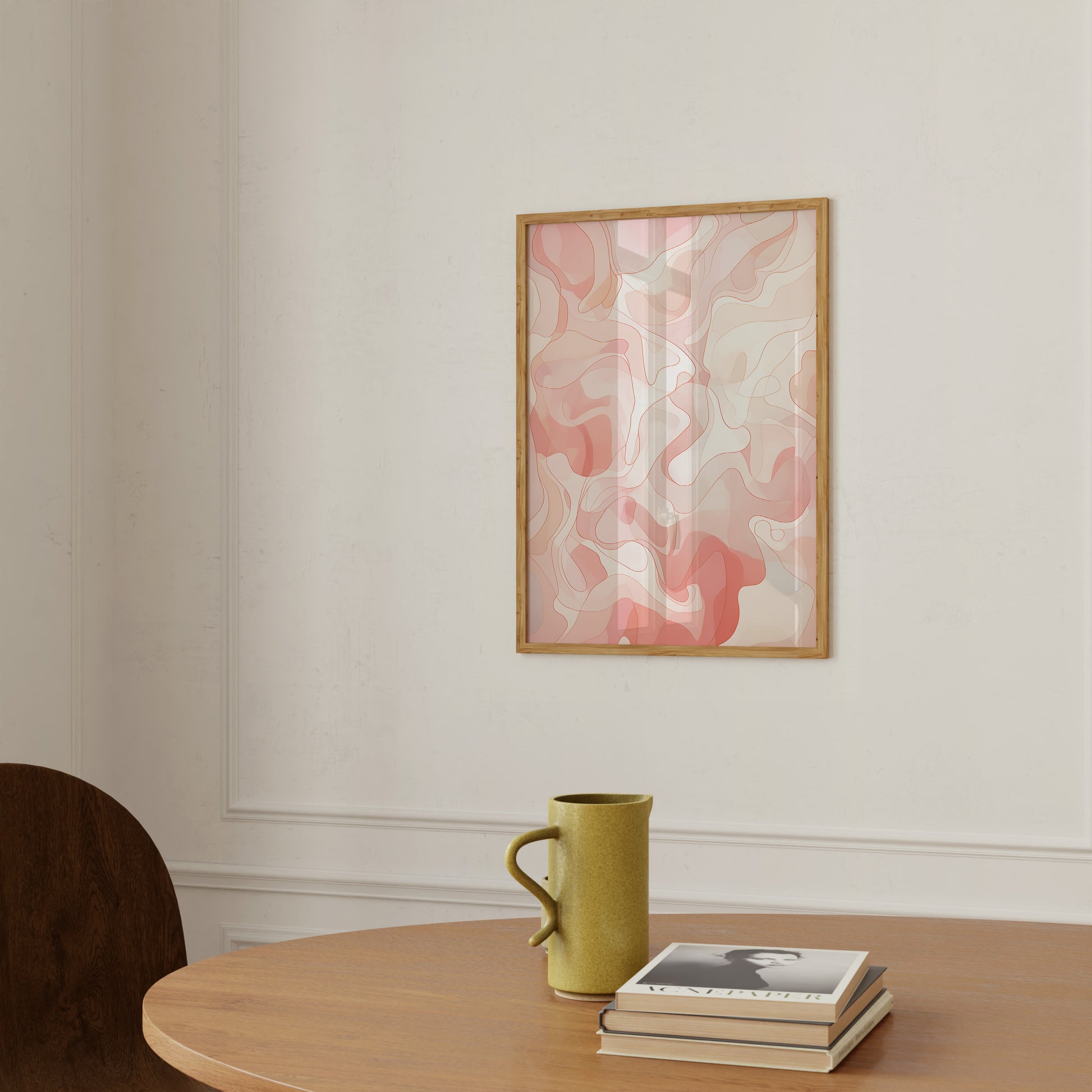 An abstract painting on a wall above a table with a yellow mug and books.