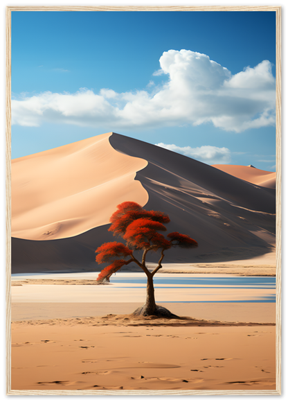 Framed image of a solitary tree with red leaves against large sand dunes under a blue sky with clouds.