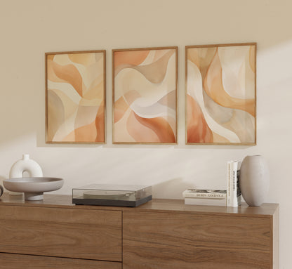 Three abstract paintings in warm tones hanging above a wooden sideboard with decorative items.