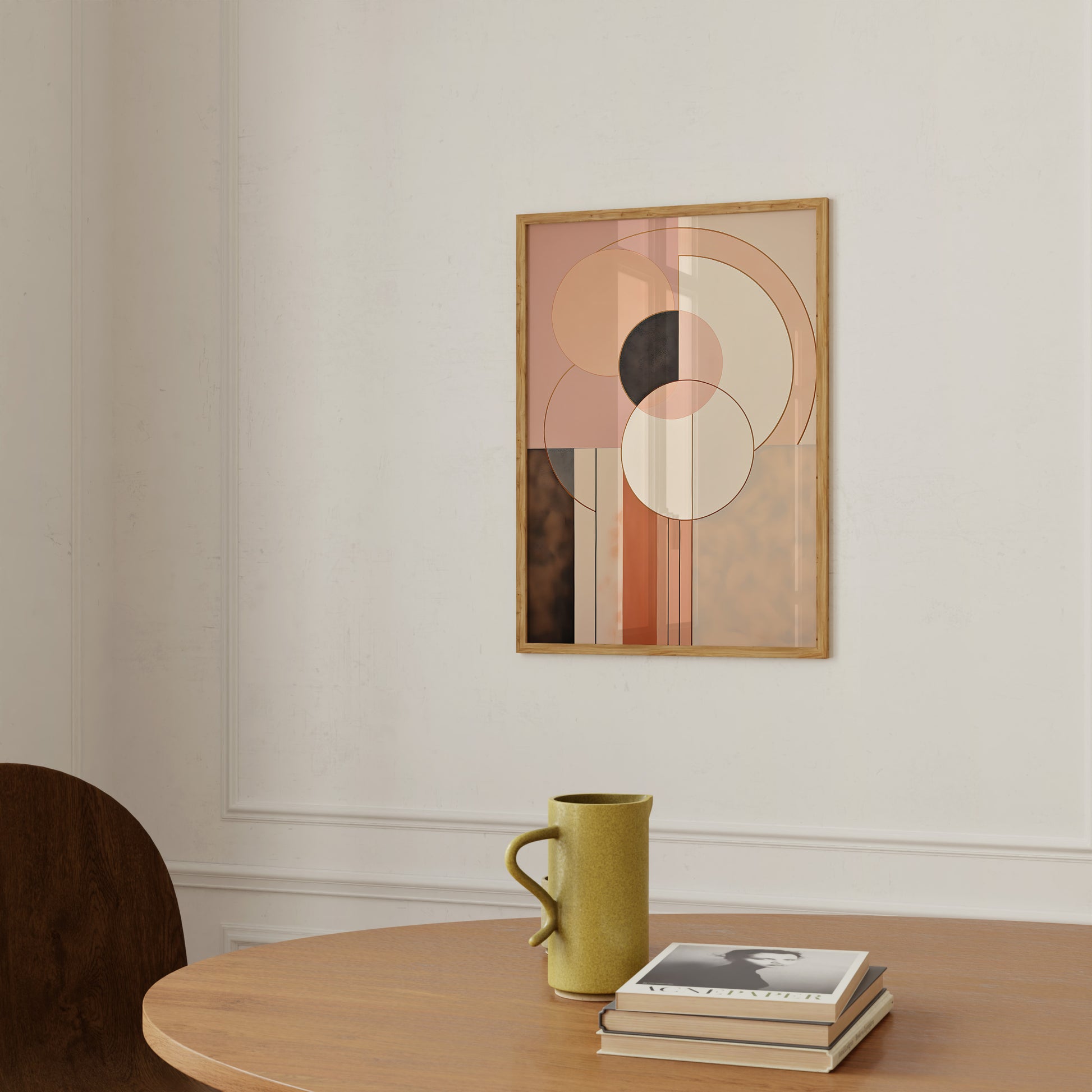 Abstract wall art with geometric shapes above a table with a mug and books.
