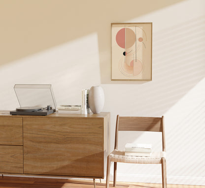 A minimalist interior with a record player on a wooden cabinet, next to a framed abstract art piece and a chair.