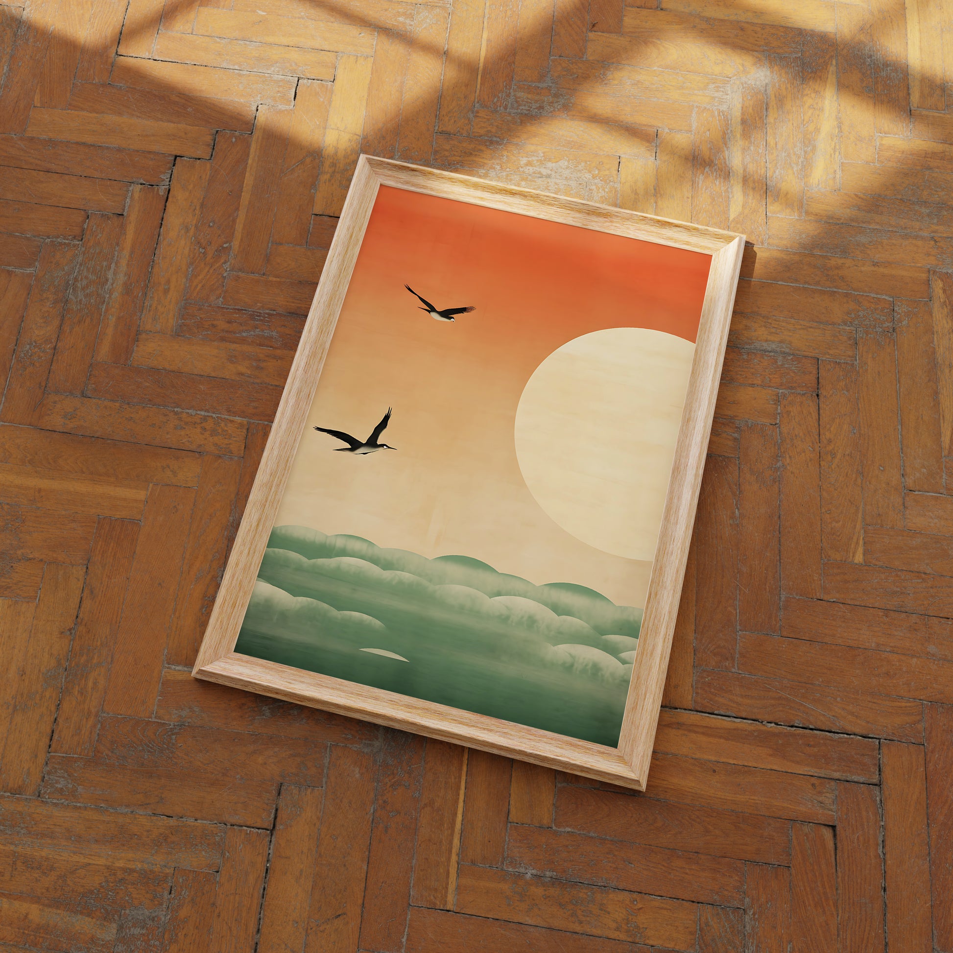 A framed painting of a sunset with birds flying over clouds, on a wooden floor.