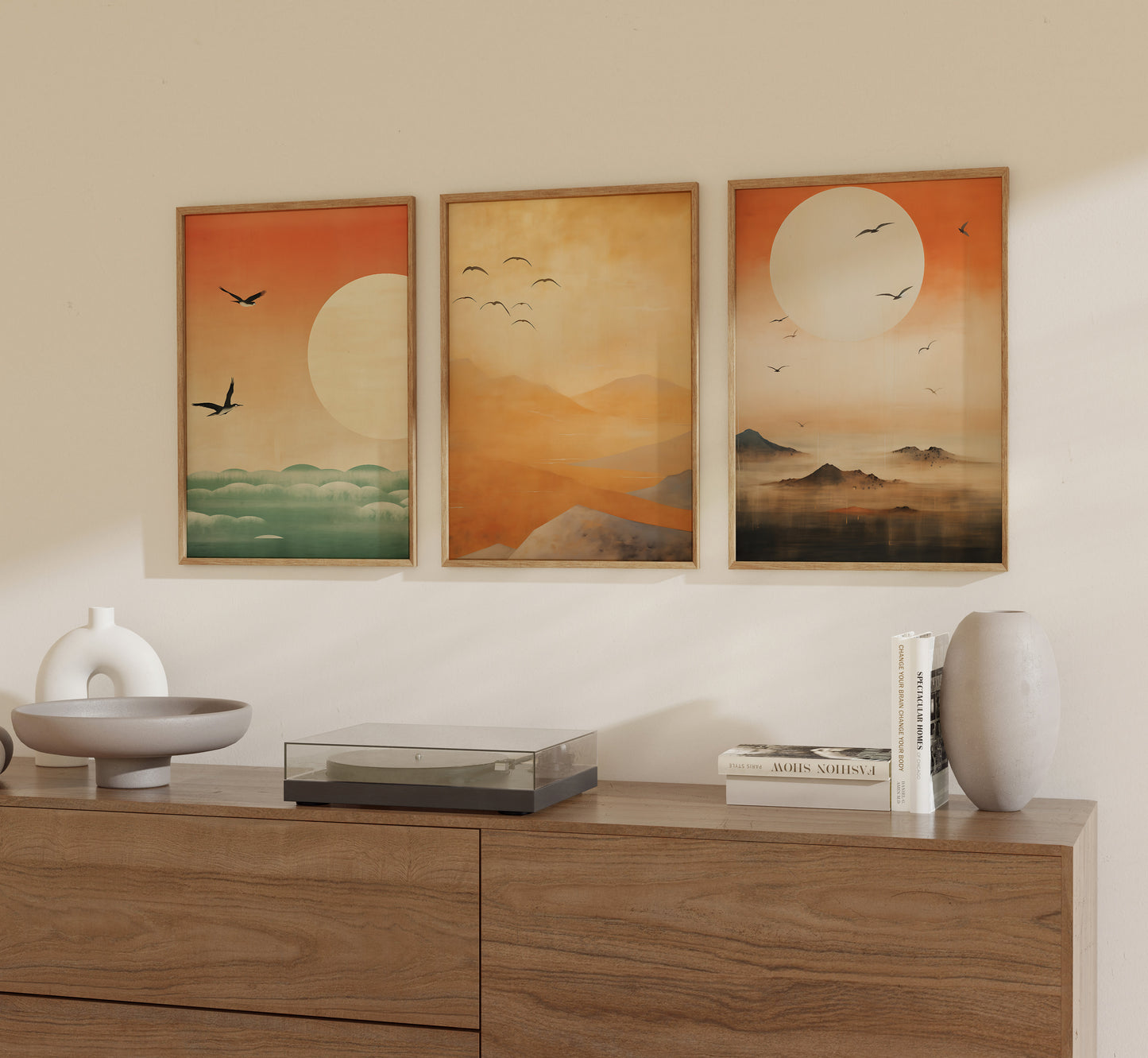 Three framed artworks of sunsets on a wall above a wooden sideboard with decorative items.
