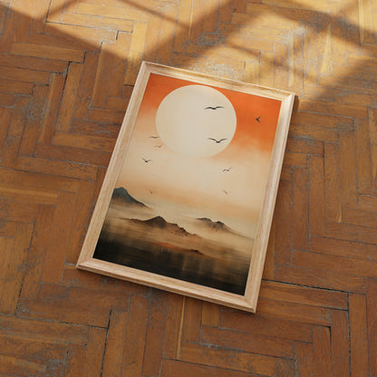 A framed painting of a sunset over mountains with birds in flight, lying on a wood parquet floor.
