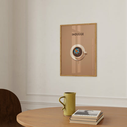 An elegant poster with the word "INDULGE" above a stylized circular design, hung on a wall above a table with a mug and books.