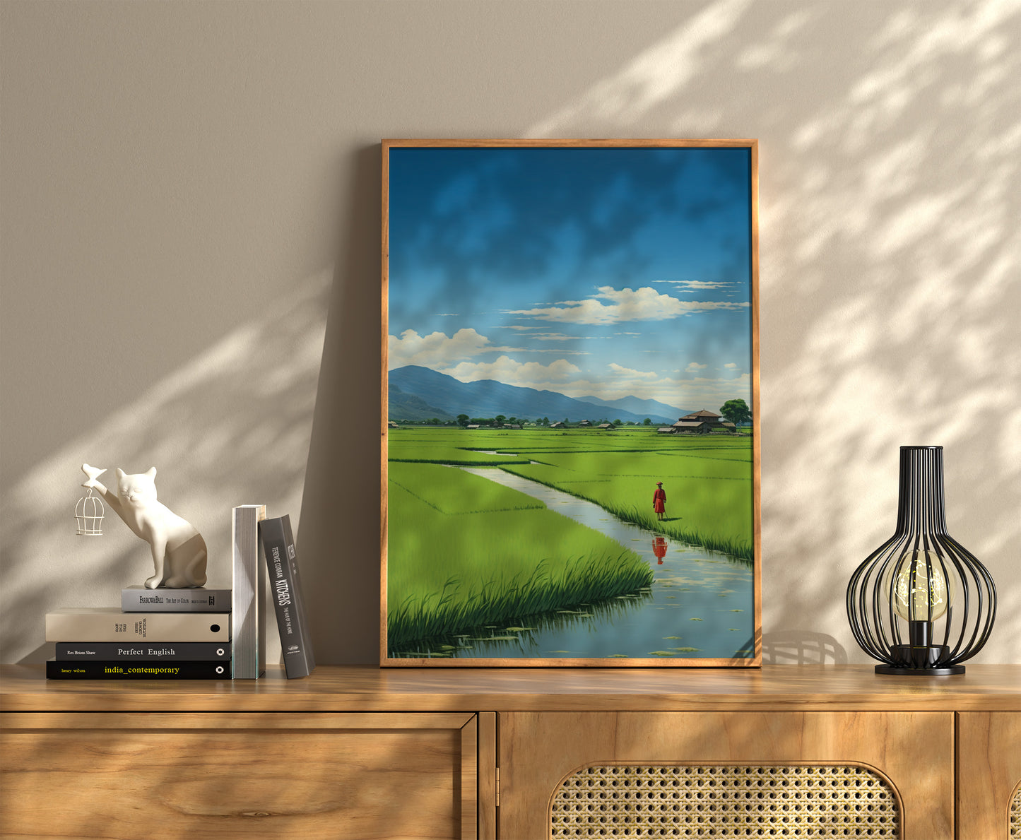 A framed landscape painting on a wall above a wooden sideboard with books and decor items.