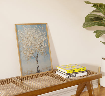 Painting of a tree on a side table with books against a neutral wall next to a plant.