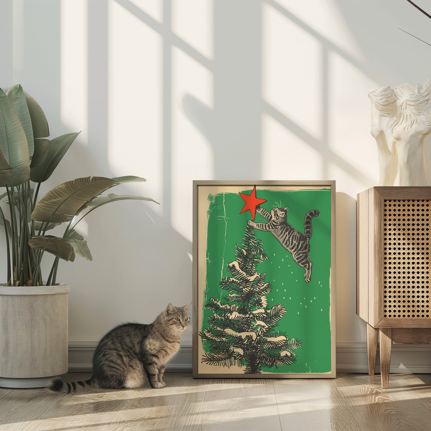 A cat staring at a framed picture of a cat jumping towards a Christmas tree.