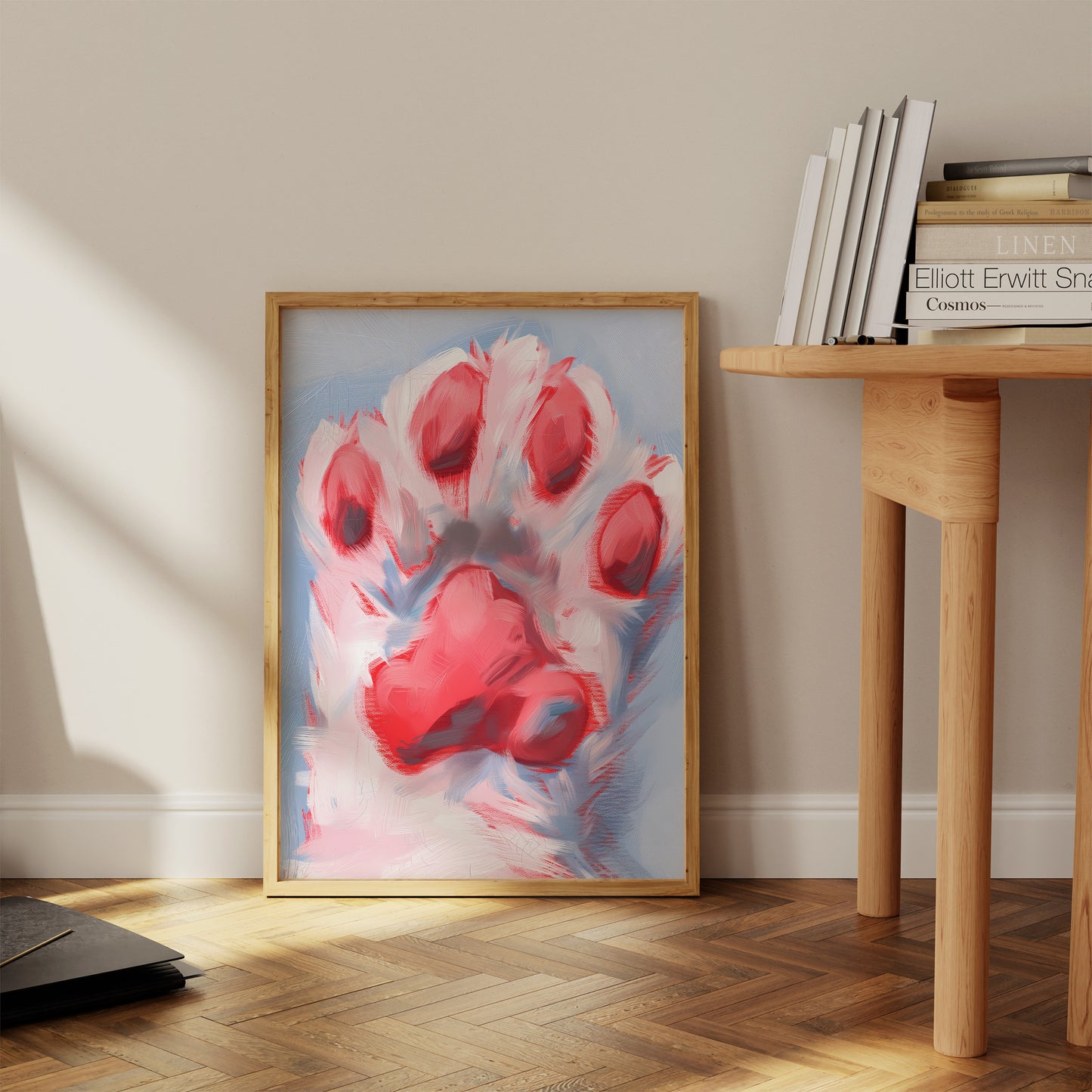 A large framed painting of a red paw print leaning against a wall in a sunny room.