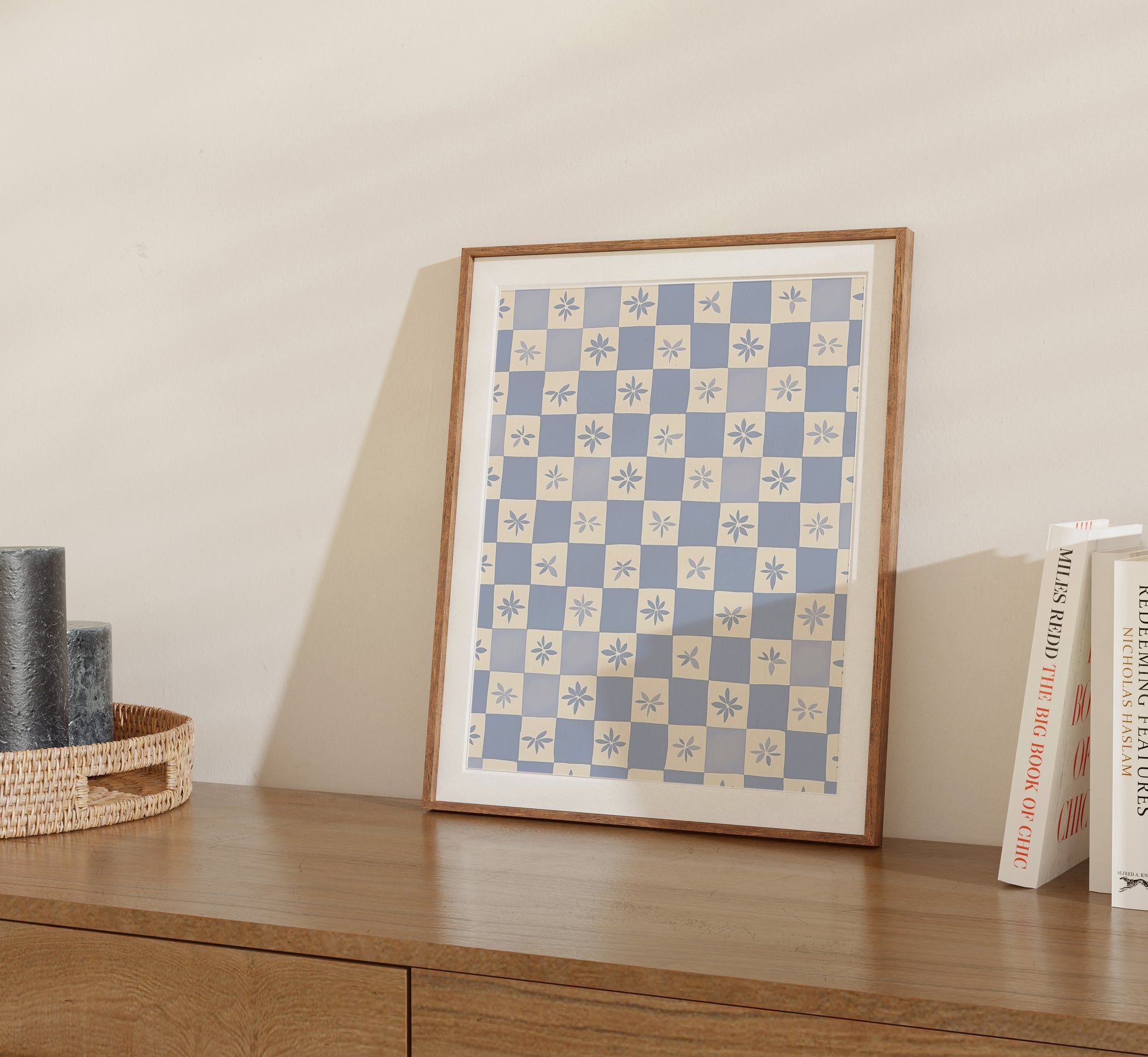 Framed geometric pattern artwork displayed on a wooden sideboard next to books and a basket.